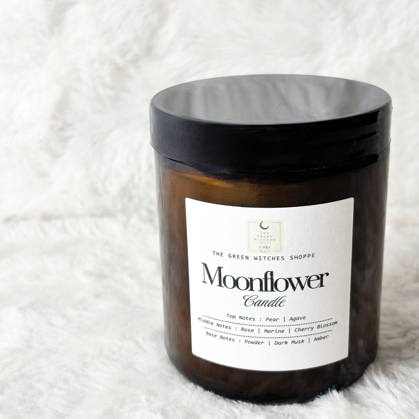 Moonflower candle with a black lid on a white fluffy blanket
