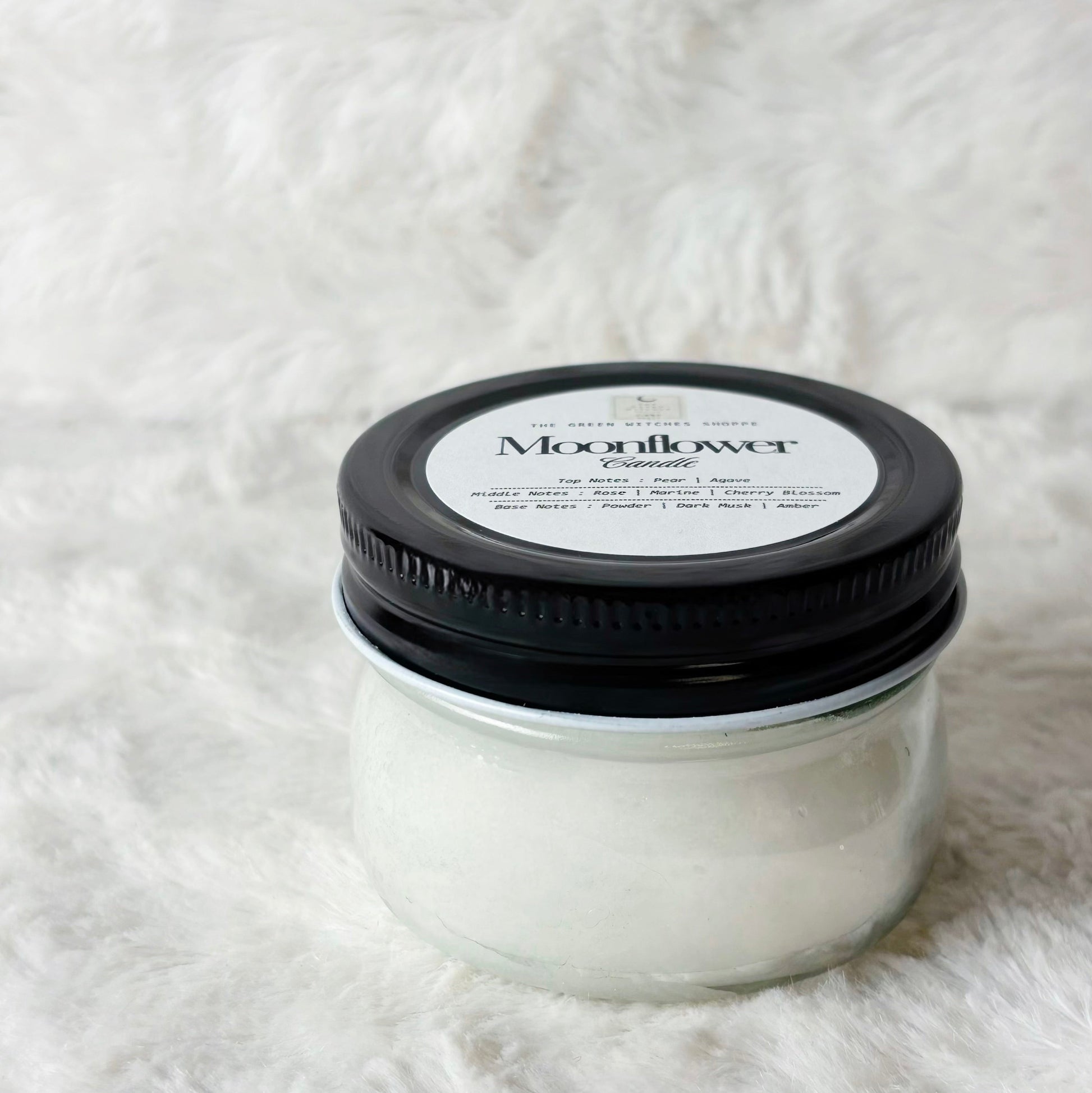 Jar of cream with a black lid on a white textured surface