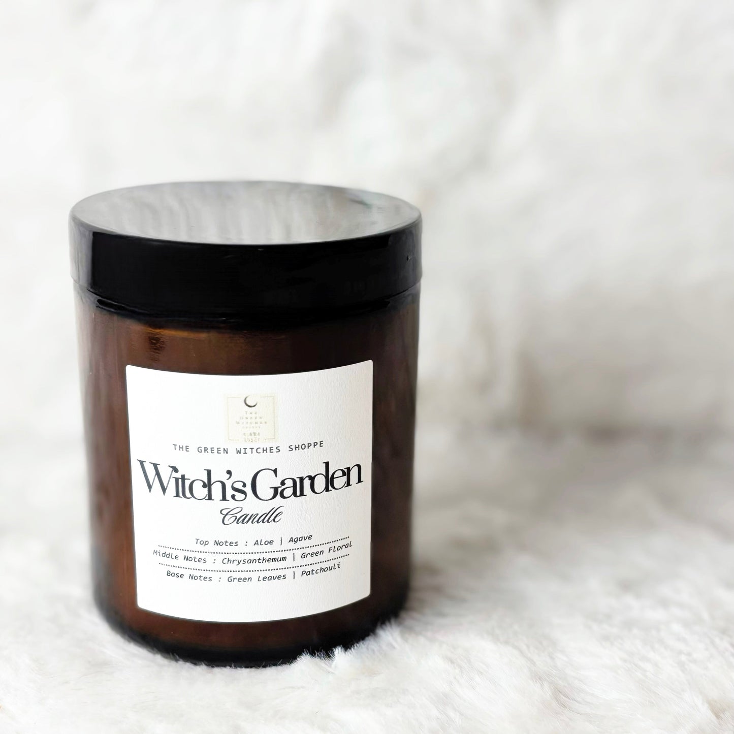 Witch's Garden candle in amber jar with black lid on a white background