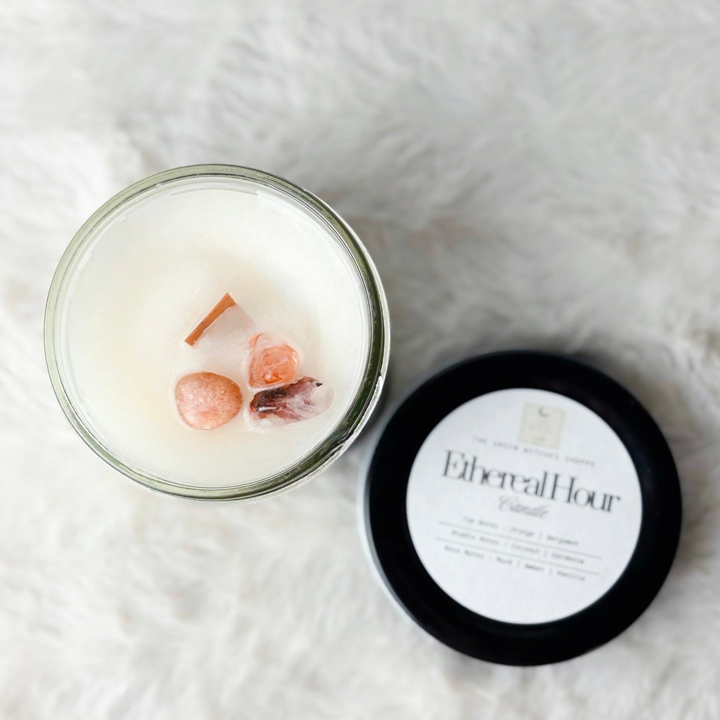 Candle in a glass jar with a black lid on a white textured surface