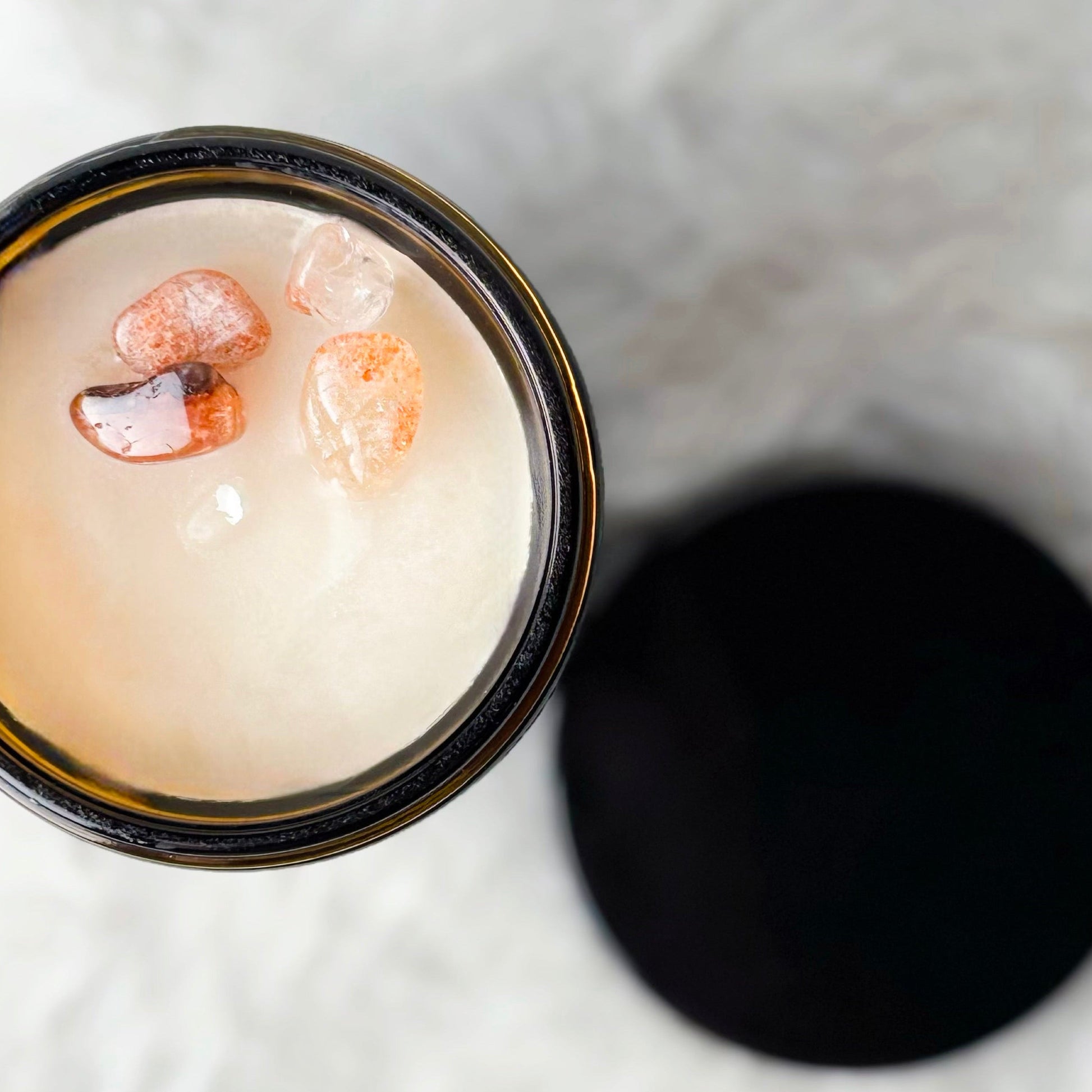 Candle in a glass jar with decorative elements on a textured white surface