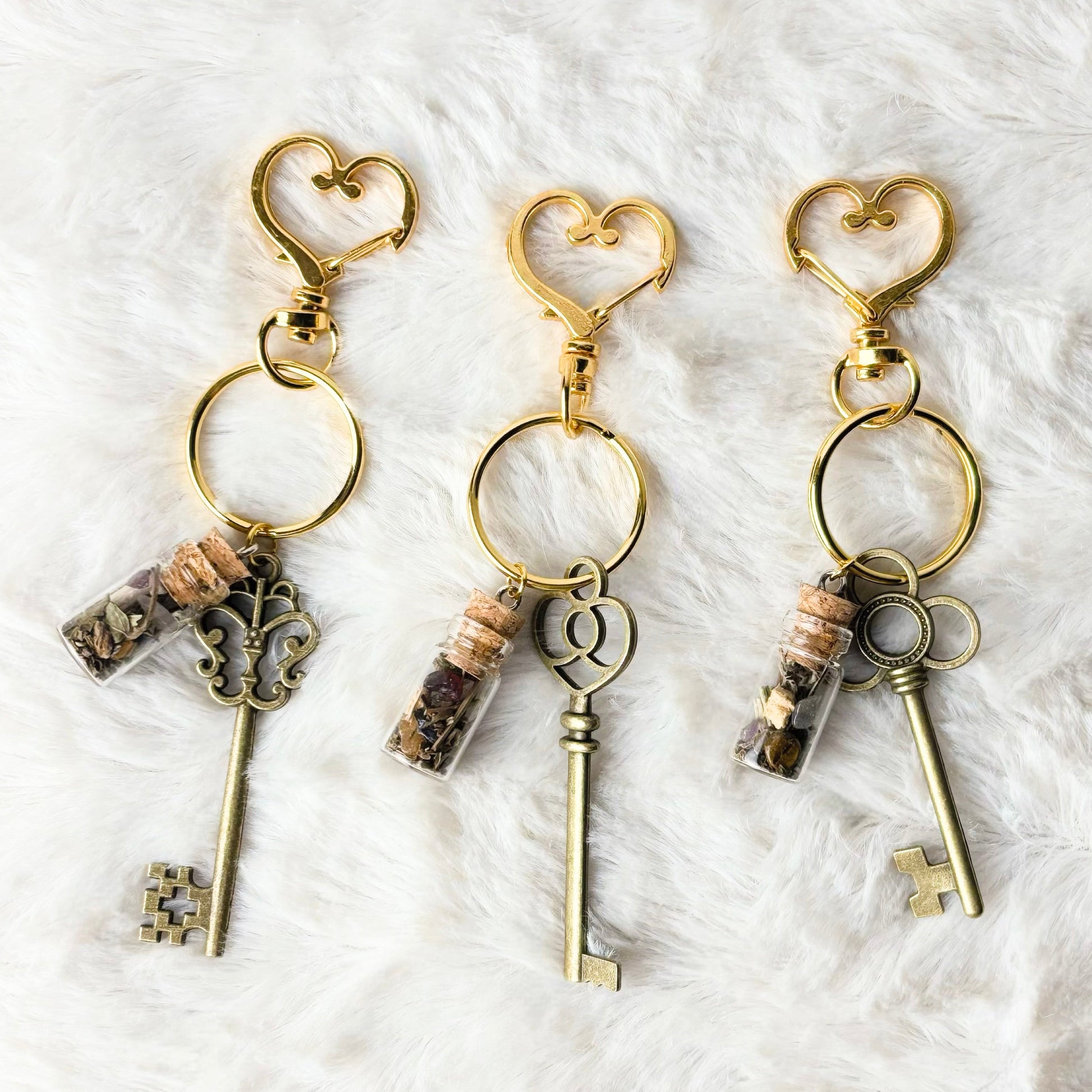 Three key-shaped keychains with heart designs on a white textured background