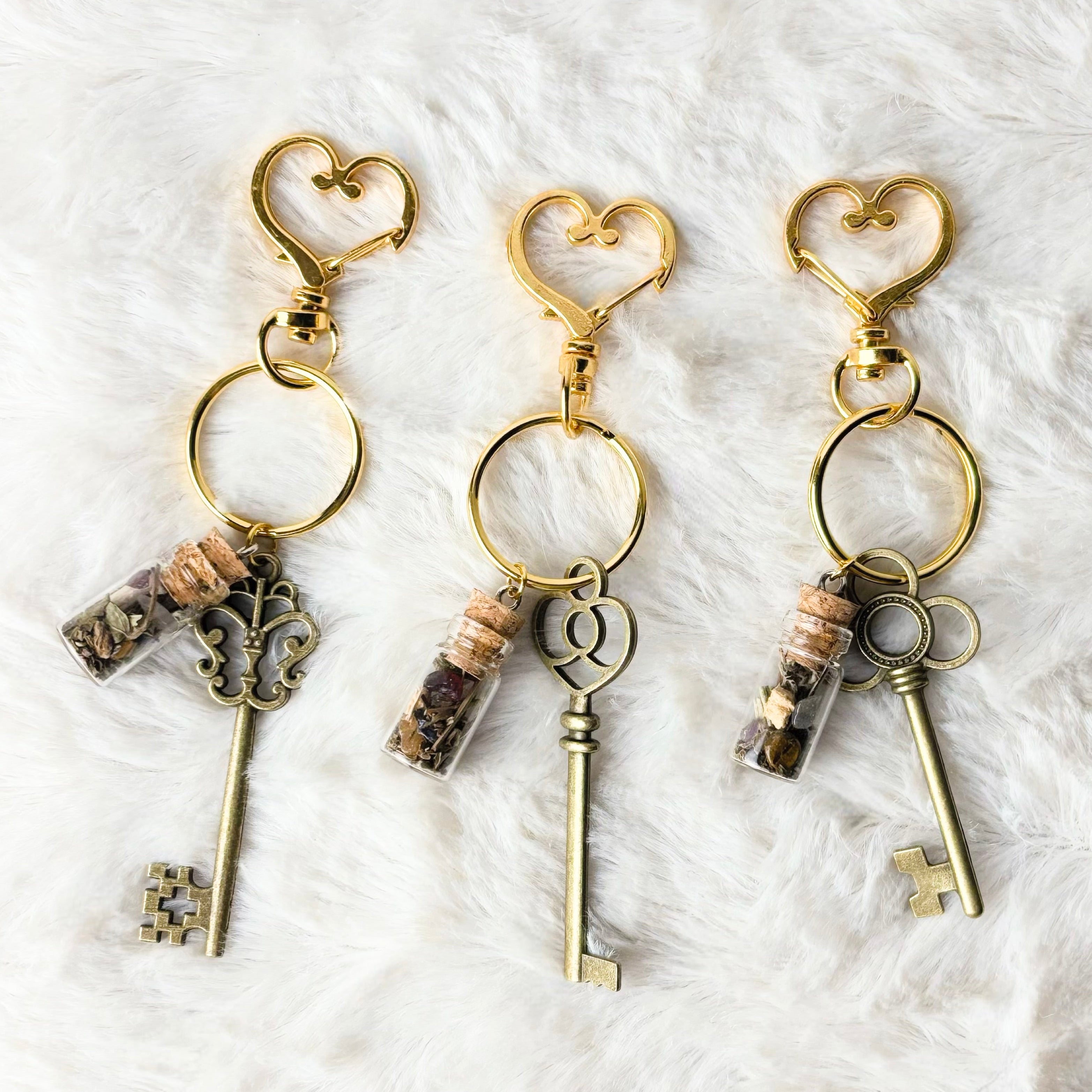 Three key-shaped keychains with heart designs on a white textured background