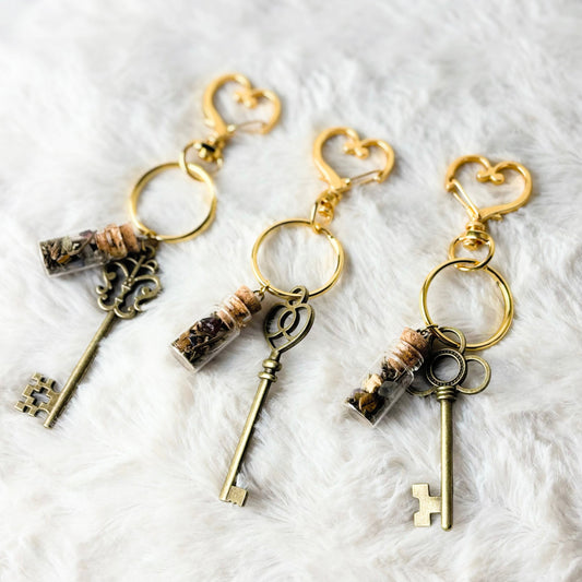 Three key-shaped keychains with decorative elements on a white textured background
