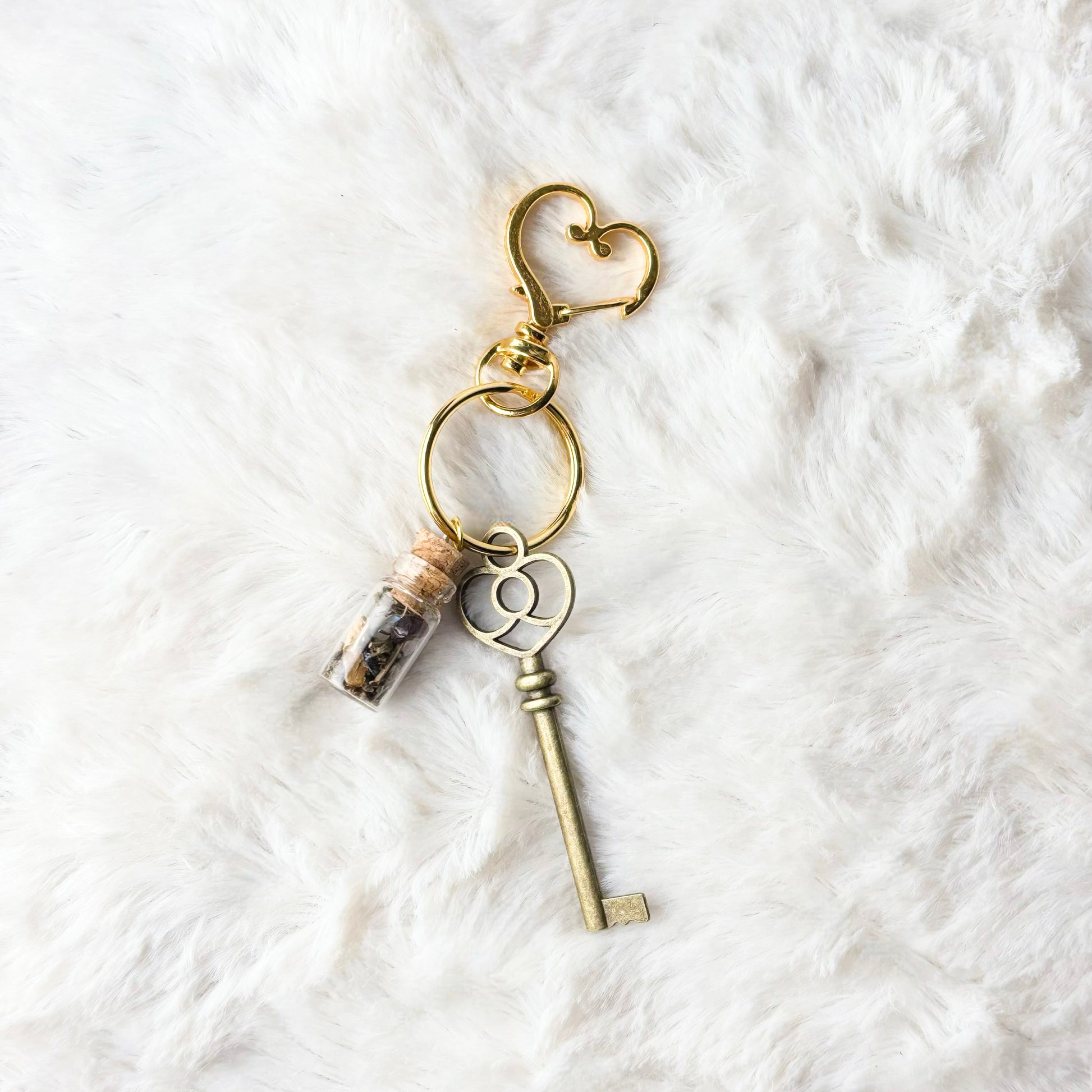 Key-shaped keychain with heart charm on a textured white surface