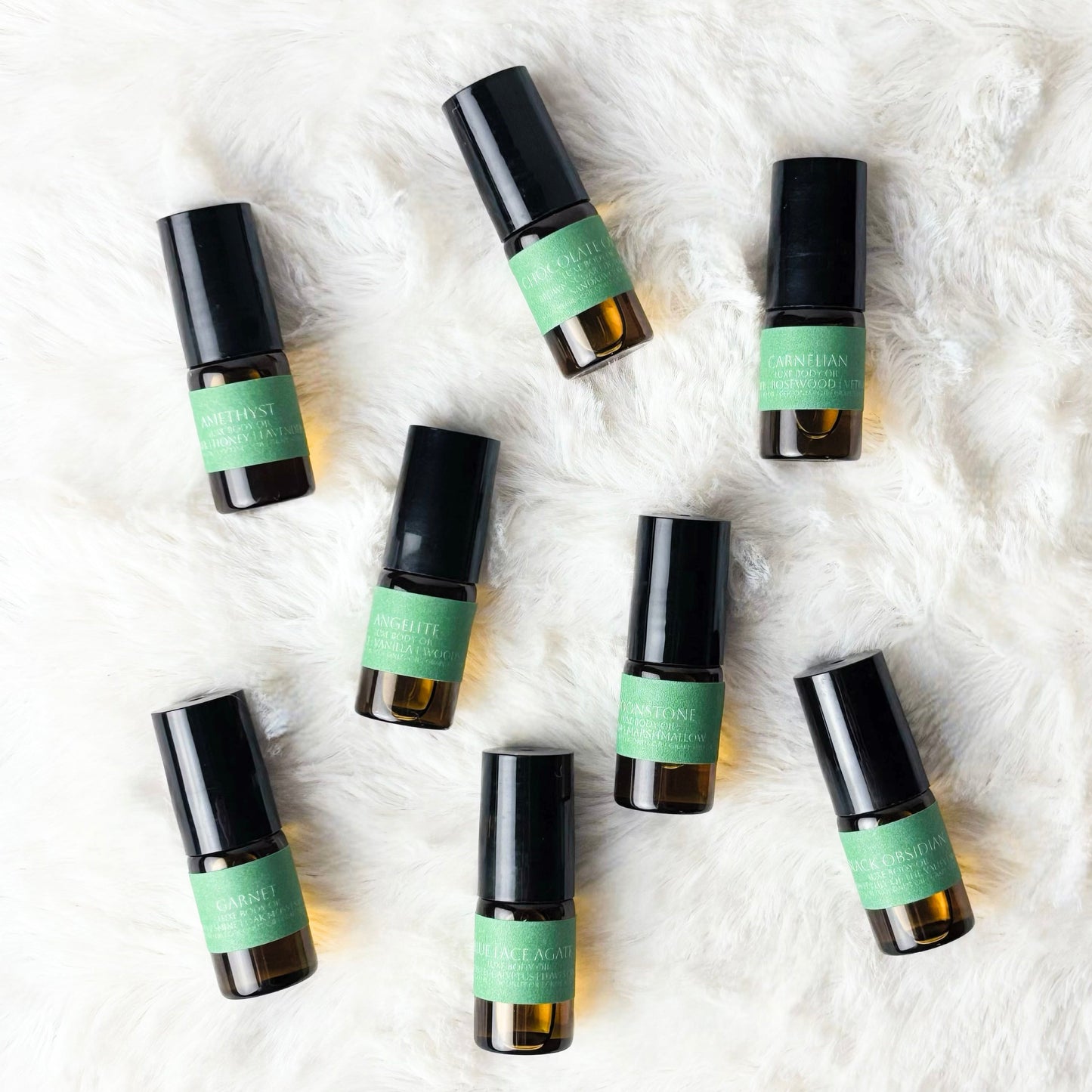 Set of small roller bottles with green labels on a textured white surface