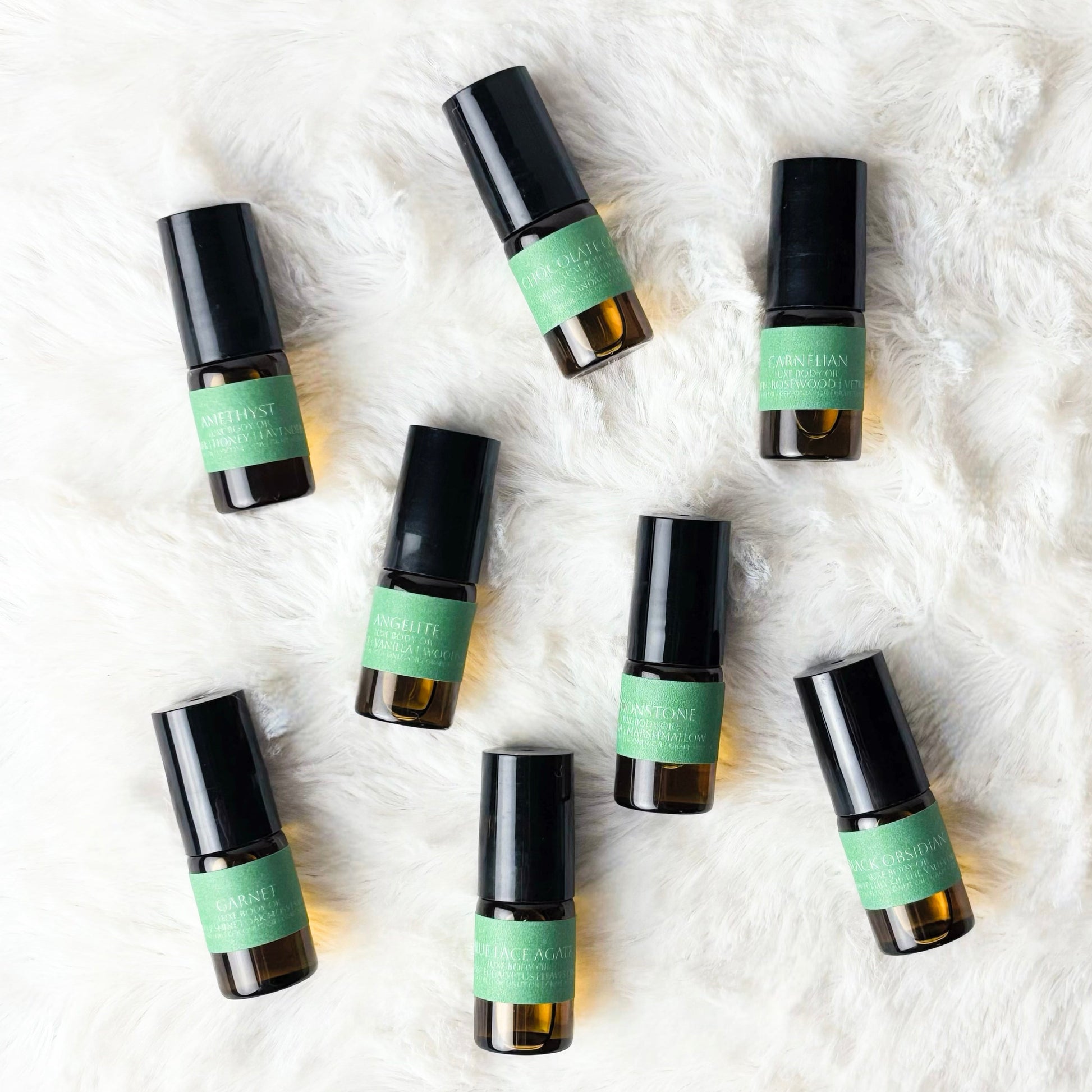 Set of small roller bottles with green labels on a textured white surface