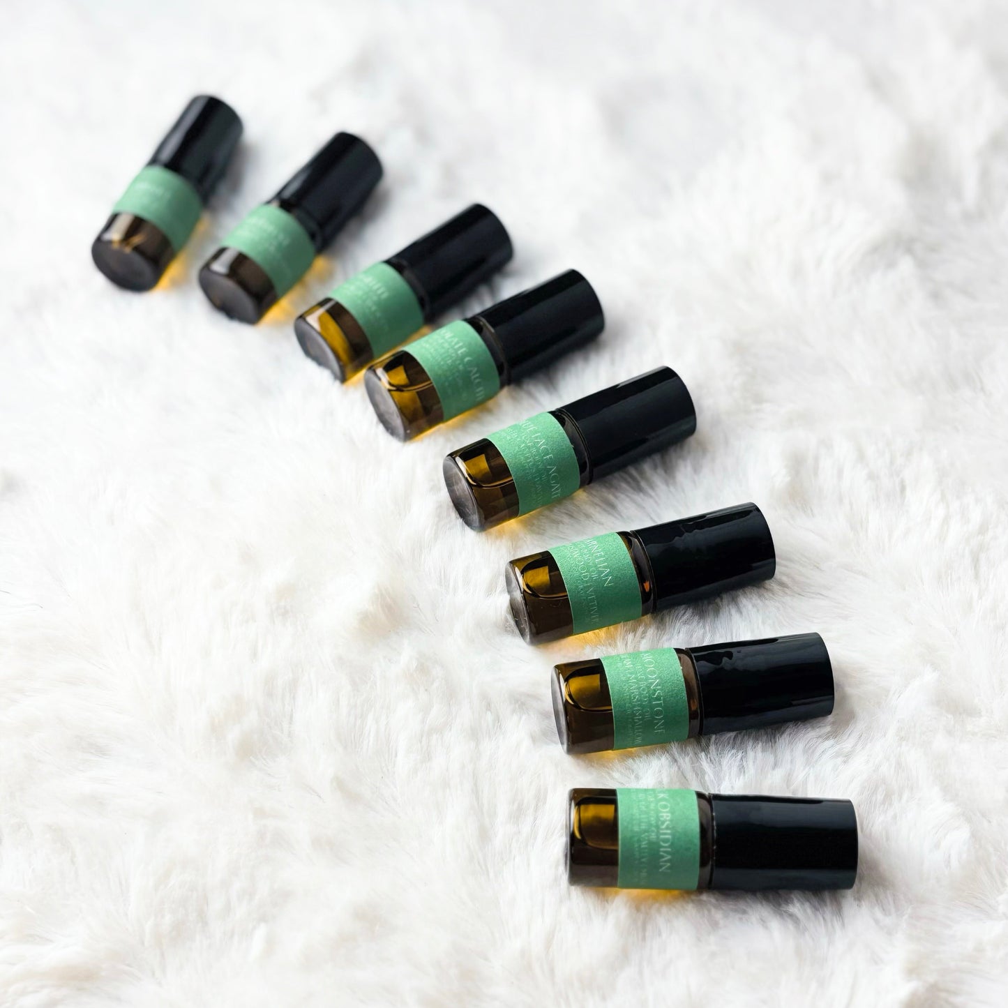 Set of essential oil roller bottles on a white textured surface