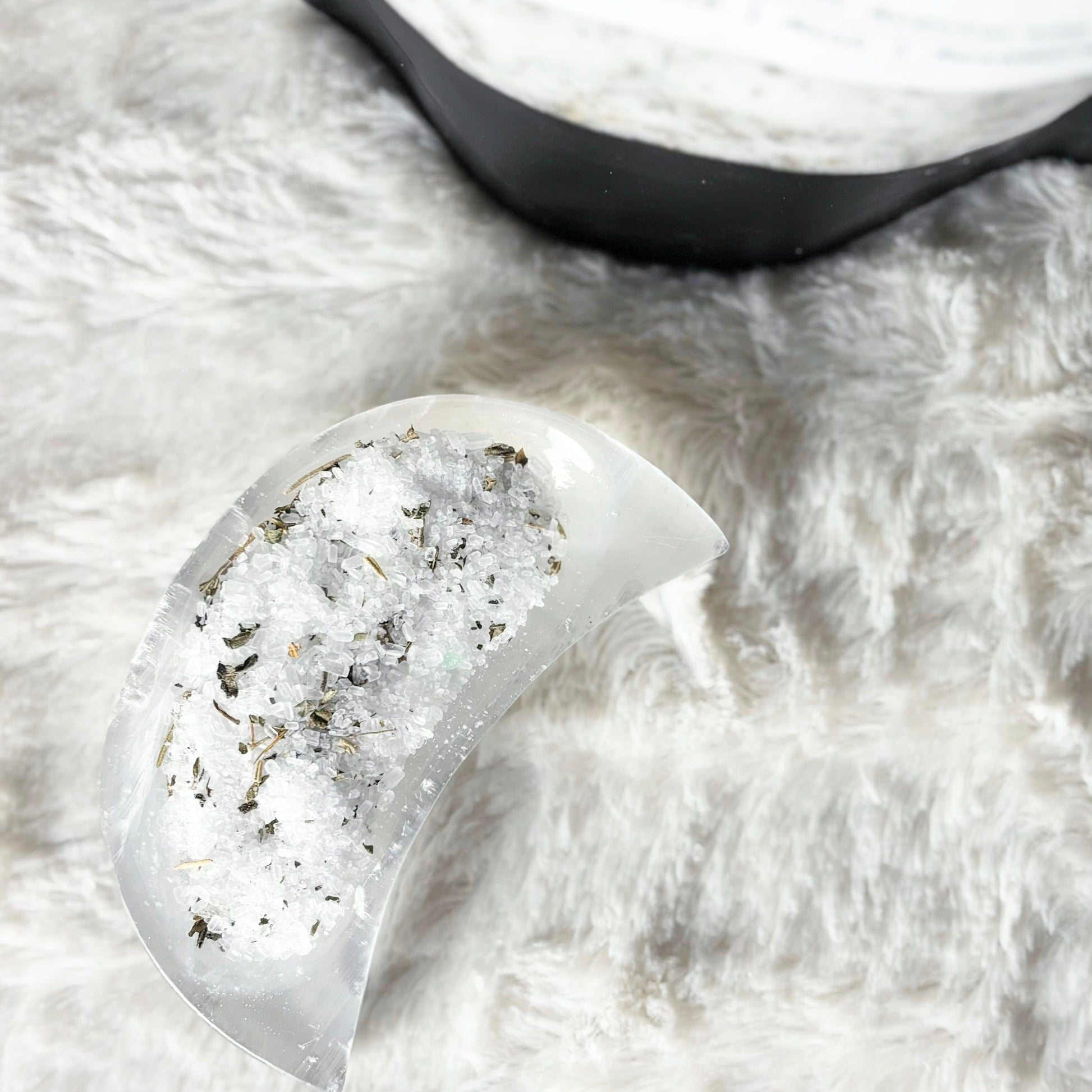Heart-shaped bath salt crystal on a fluffy white surface