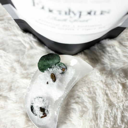 White bath soak with green leaves on a textured surface.