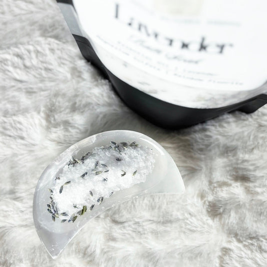 Bath soak with herbs on a fluffy white surface next to a container labeled 'Lavazza'.