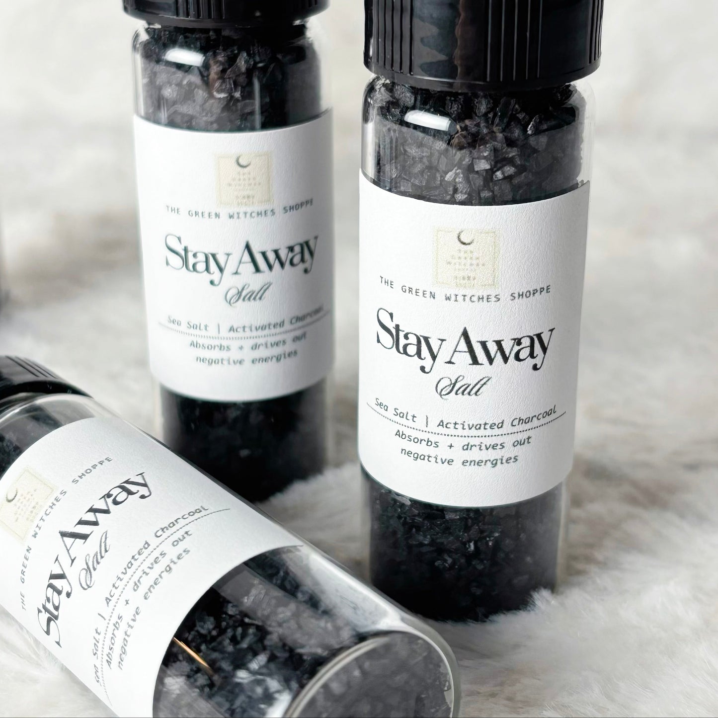 Four bottles of 'Stay Away Salt' on a textured surface