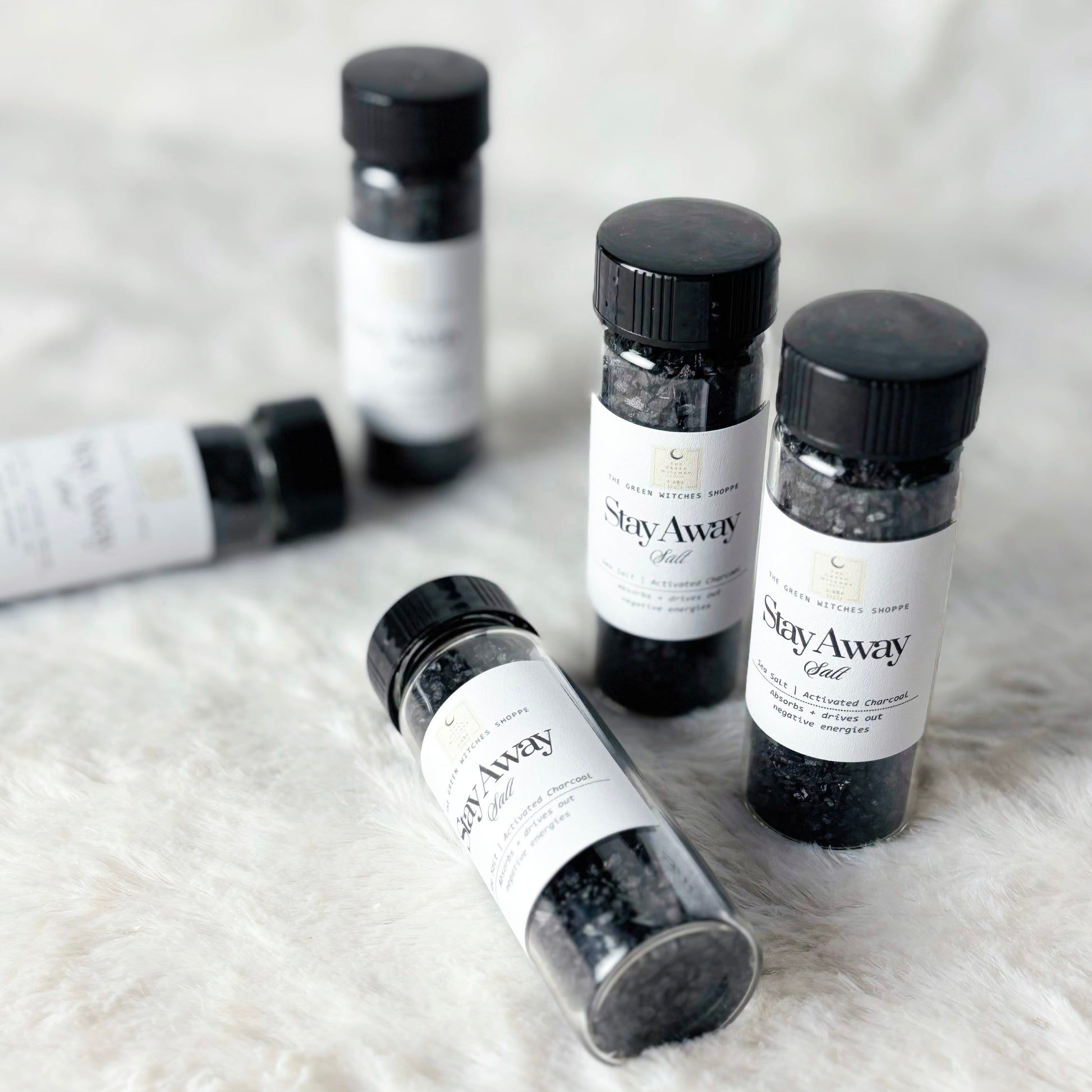 Small bottles labeled 'Stay Away' on a textured white surface