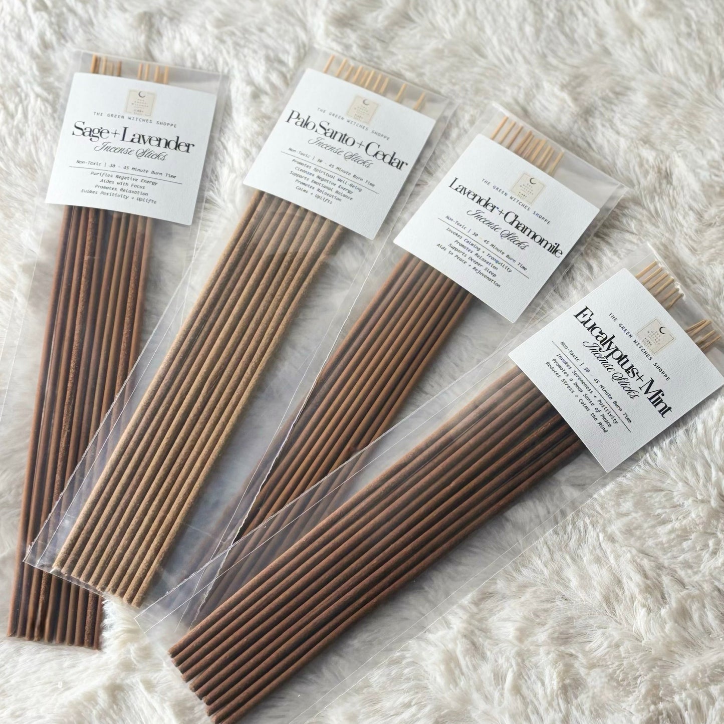Four packages of incense sticks with labels on a textured white surface