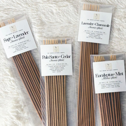 Four packages of incense sticks on a textured white surface