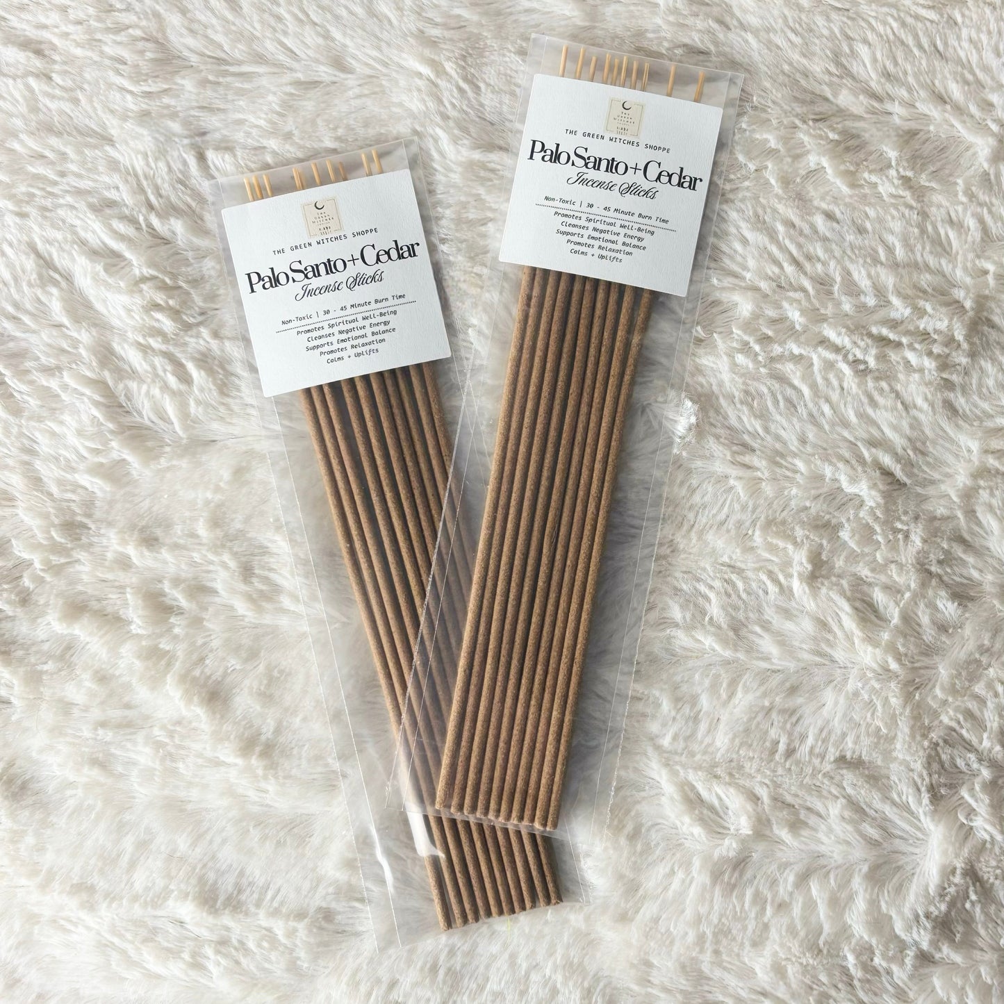 Two packages of Palo Santo + Cedar incense sticks on a textured white surface
