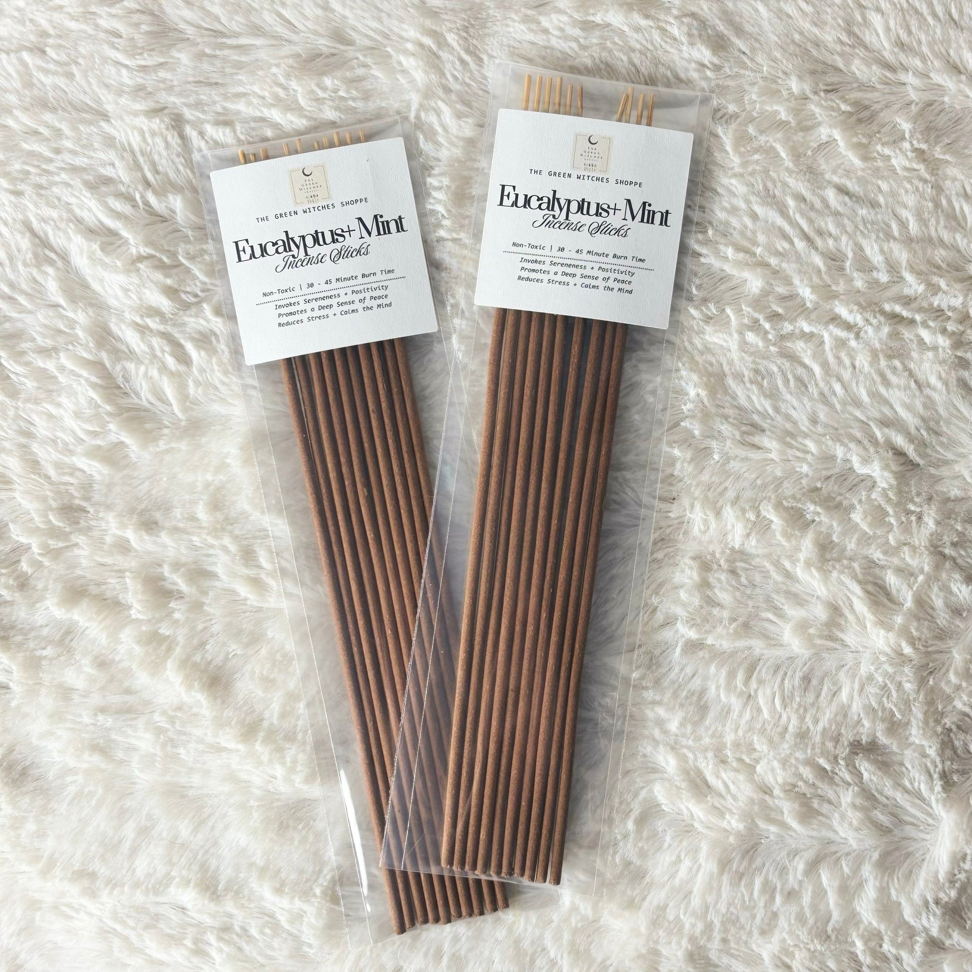 Two packages of incense sticks on a textured white surface