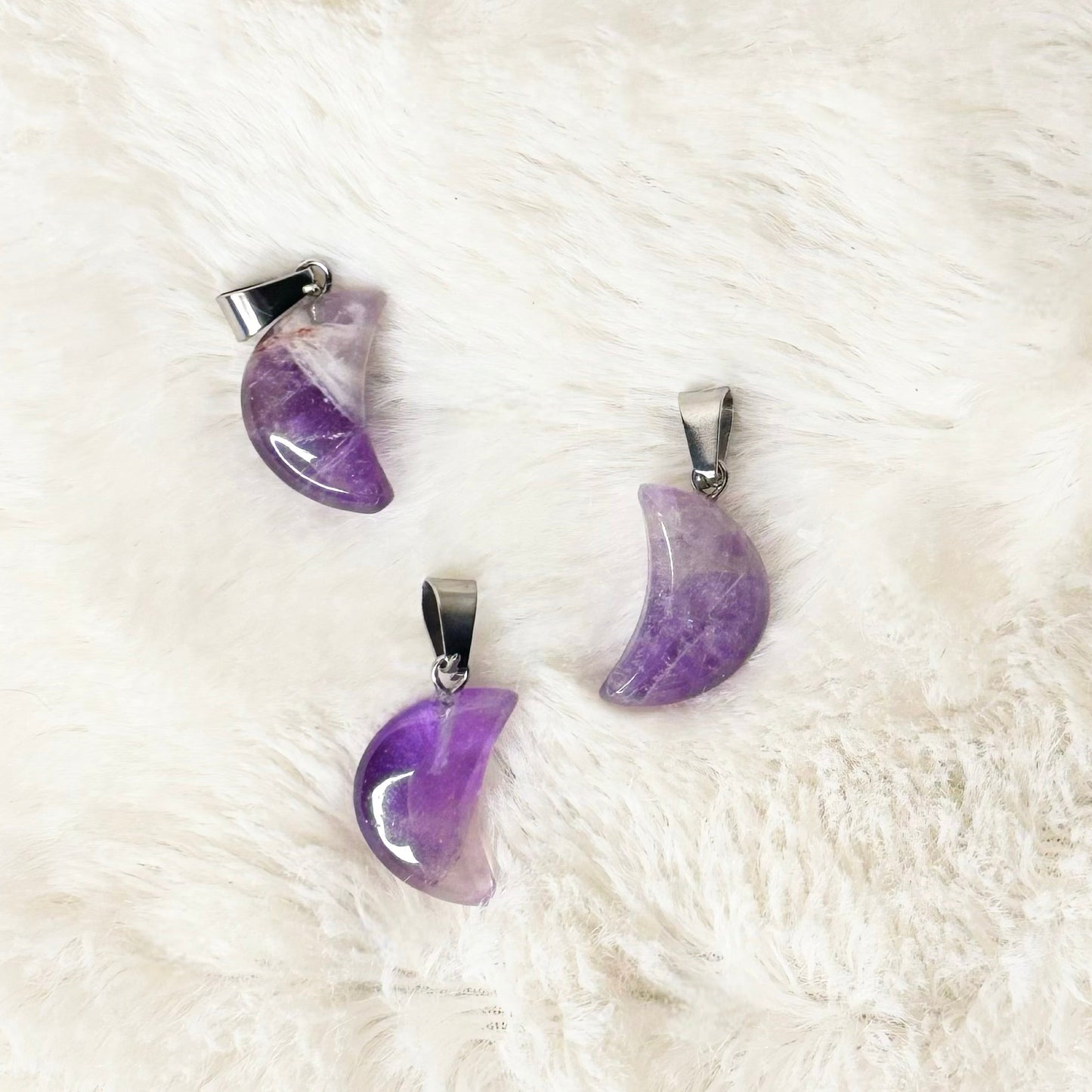 Purple crescent moon-shaped earrings on a white fur surface