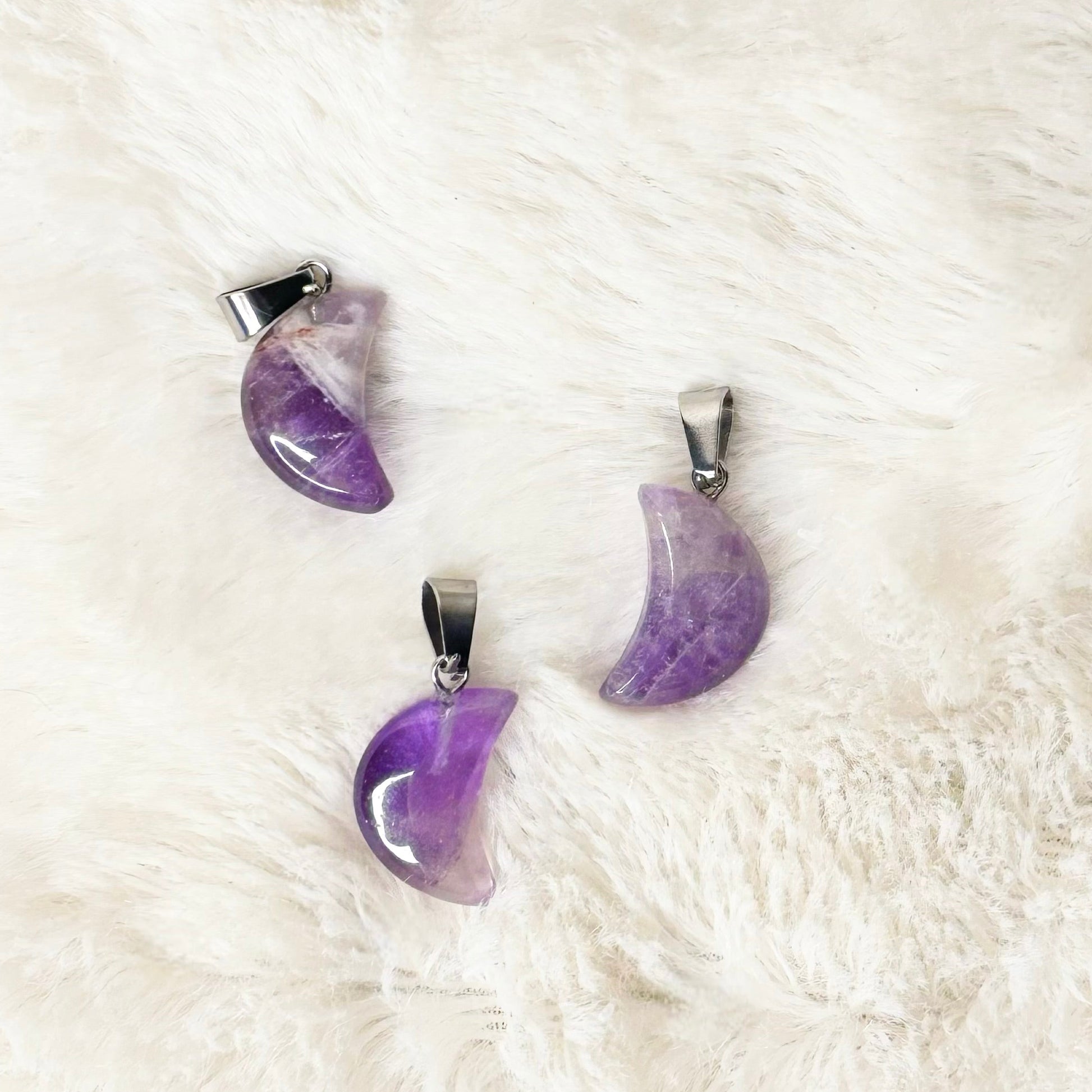 Purple crescent moon-shaped earrings on a white fur surface