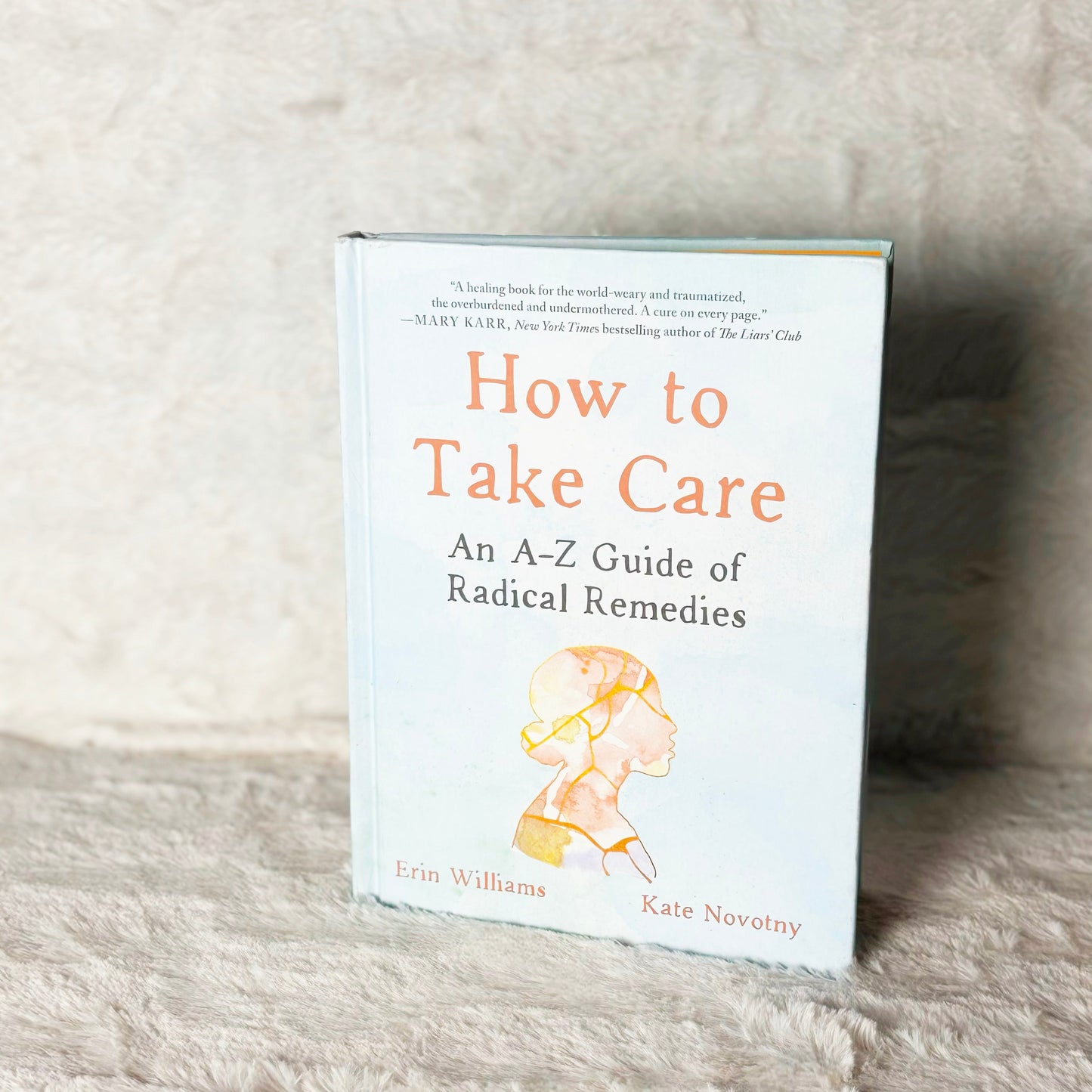Book titled 'How to Take Care: An A-Z Guide of Radical Remedies' on a textured surface