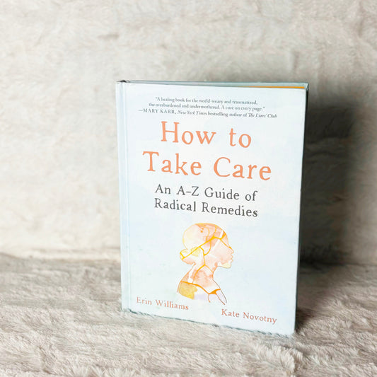 Book titled 'How to Take Care: An A-Z Guide of Radical Remedies' on a textured surface