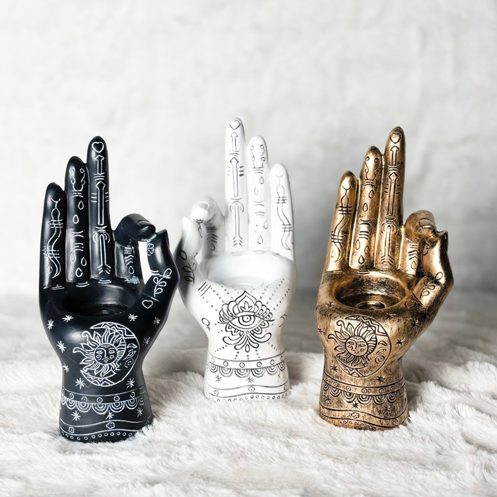 Three decorative hands in black, white, and gold on a white background