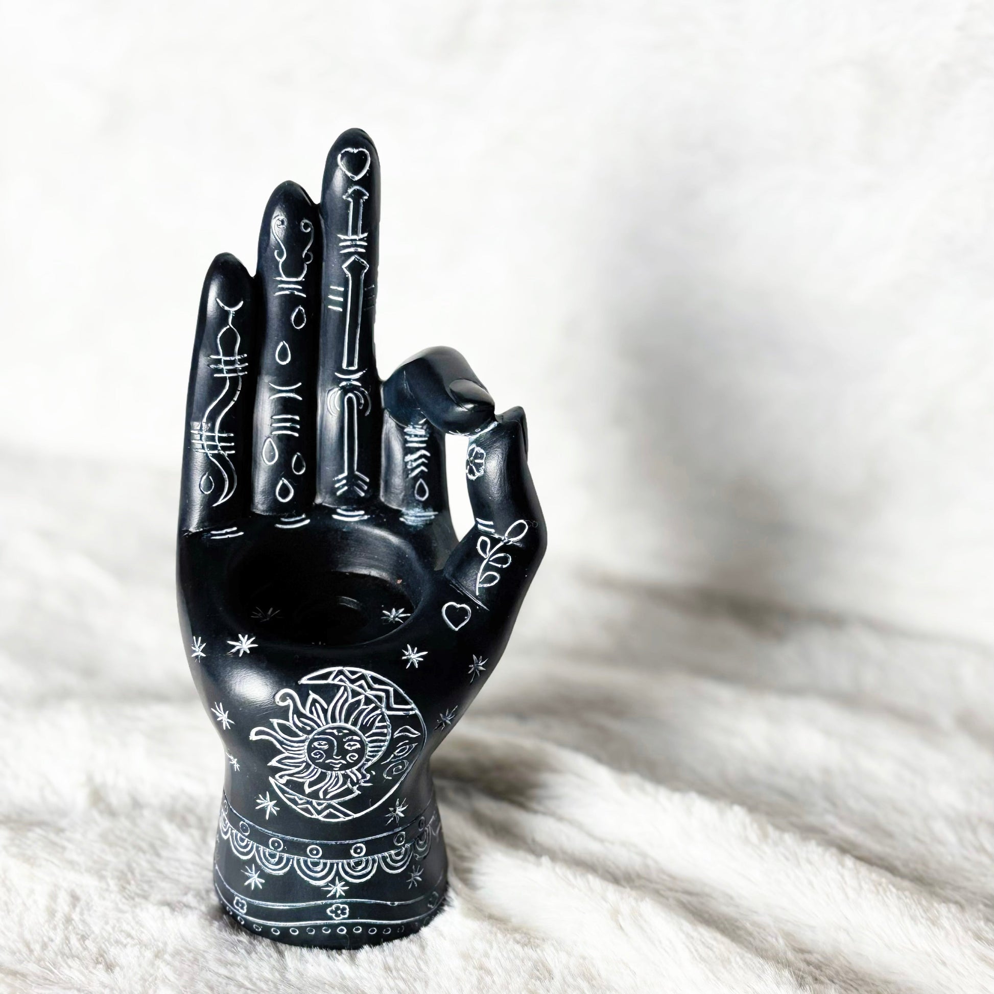 Black decorative hand with white designs on a white fur surface