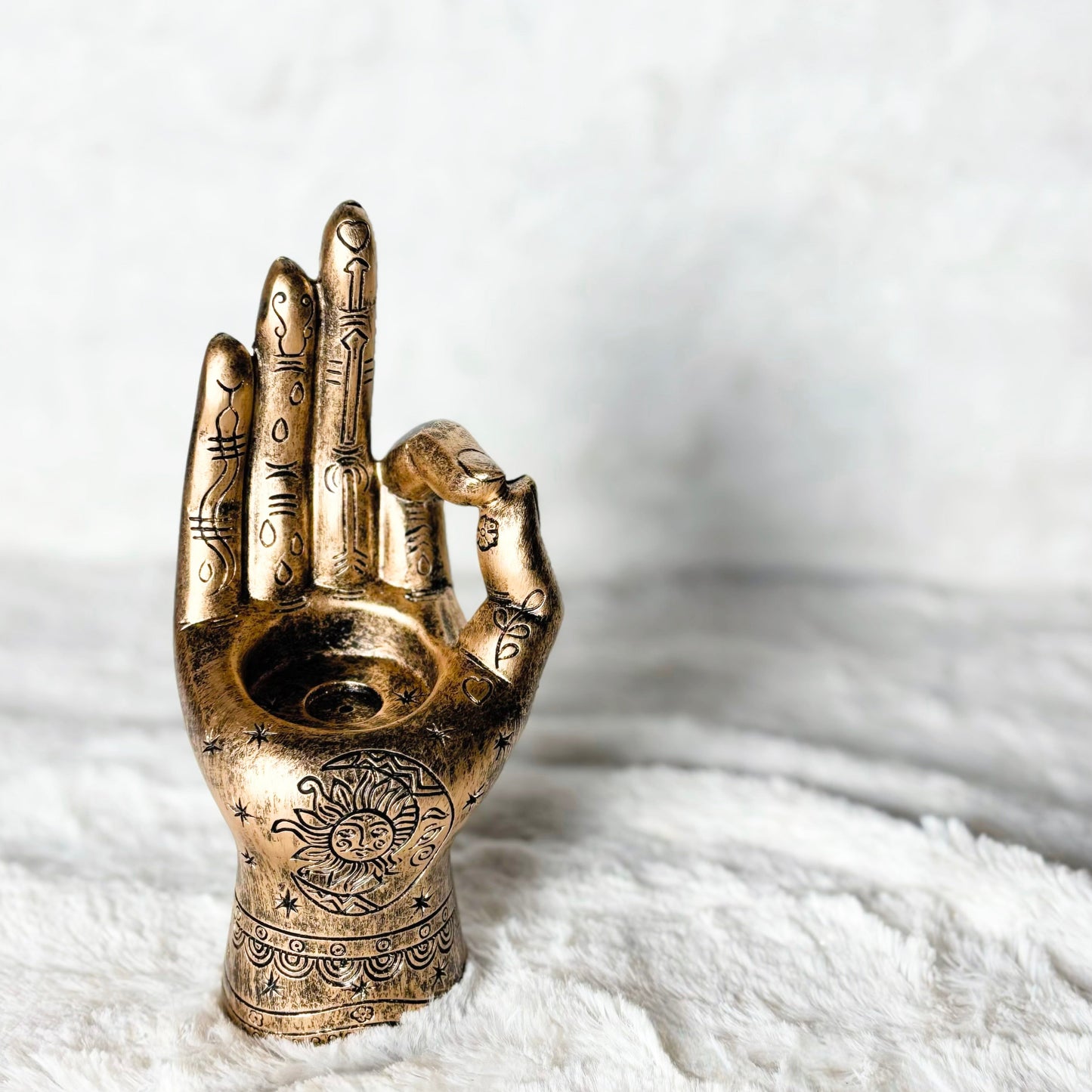 Bronze hand sculpture with a symbol on a white surface
