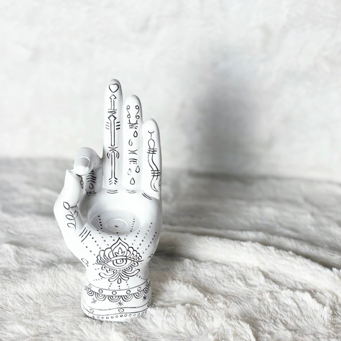 Decorative white hand with black patterns on a textured white surface