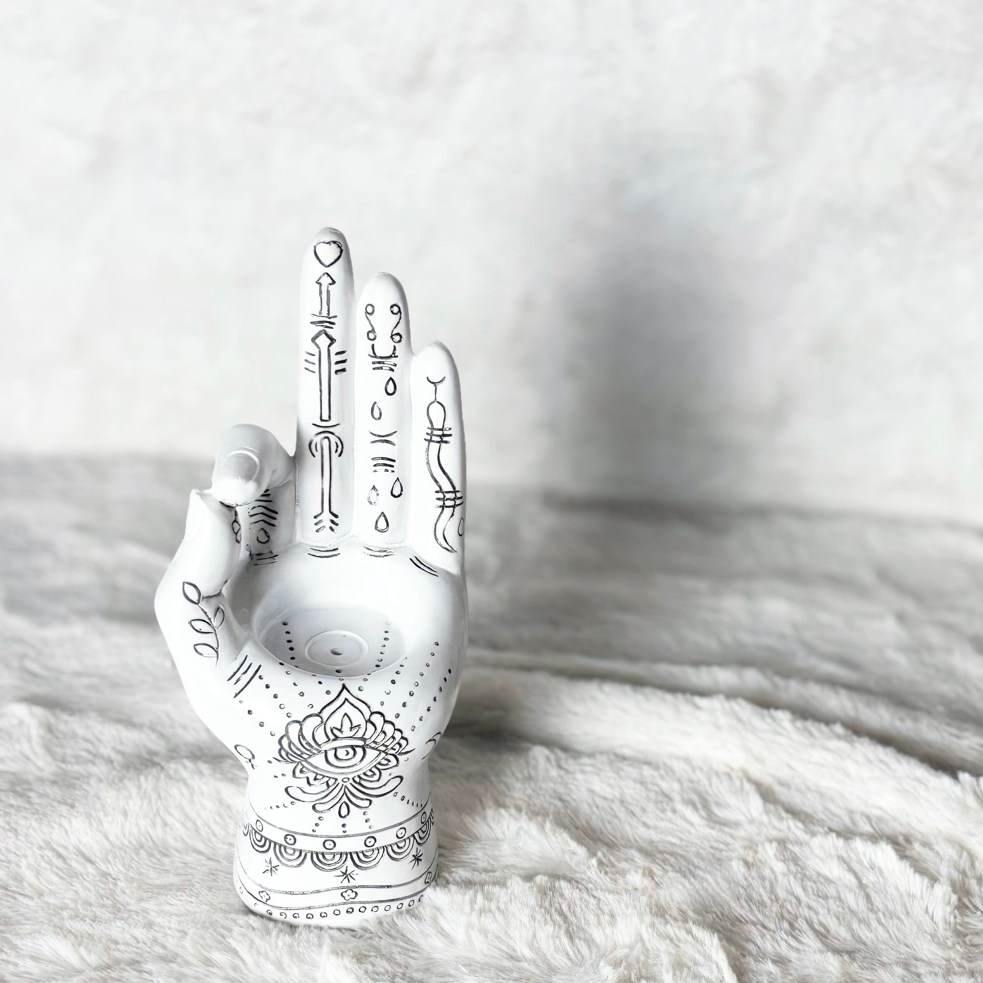 Decorative white hand with black patterns on a textured white surface