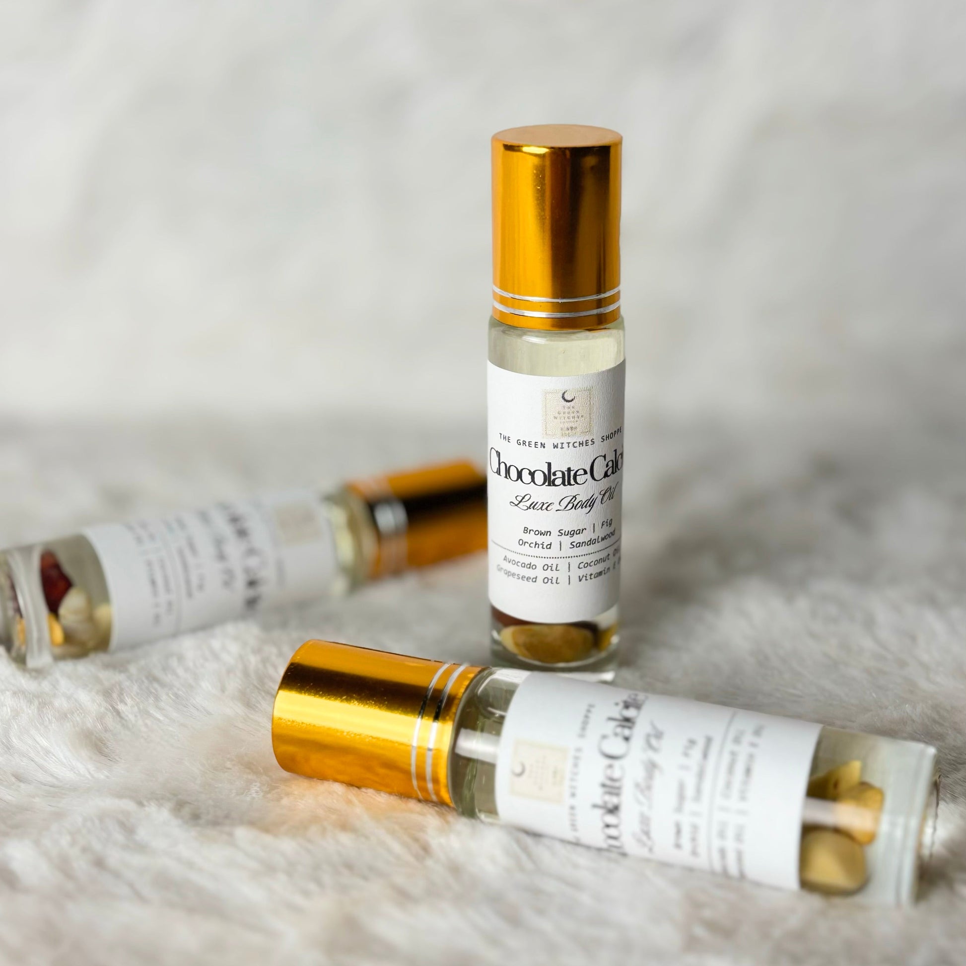 Roll-on bottles of 'Chocolate Creme' body oil on a textured white surface