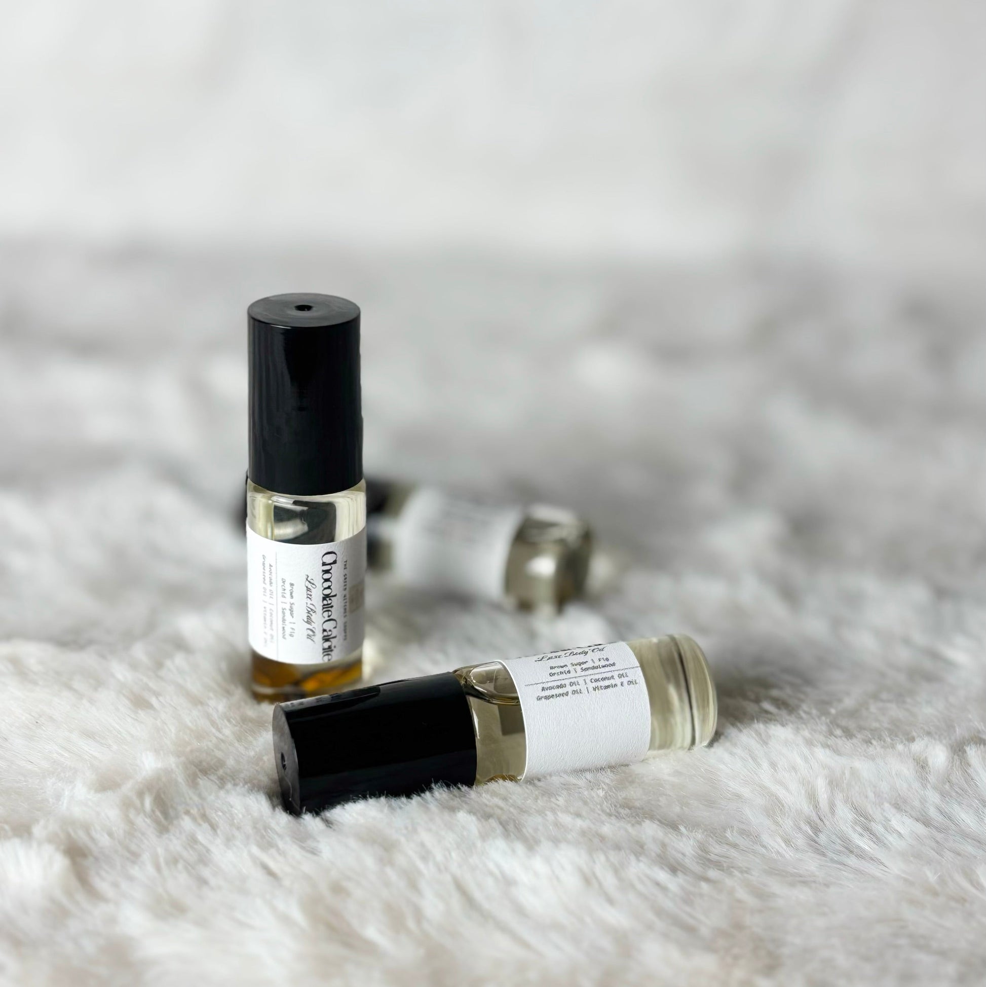 Two small perfume bottles on a textured white surface