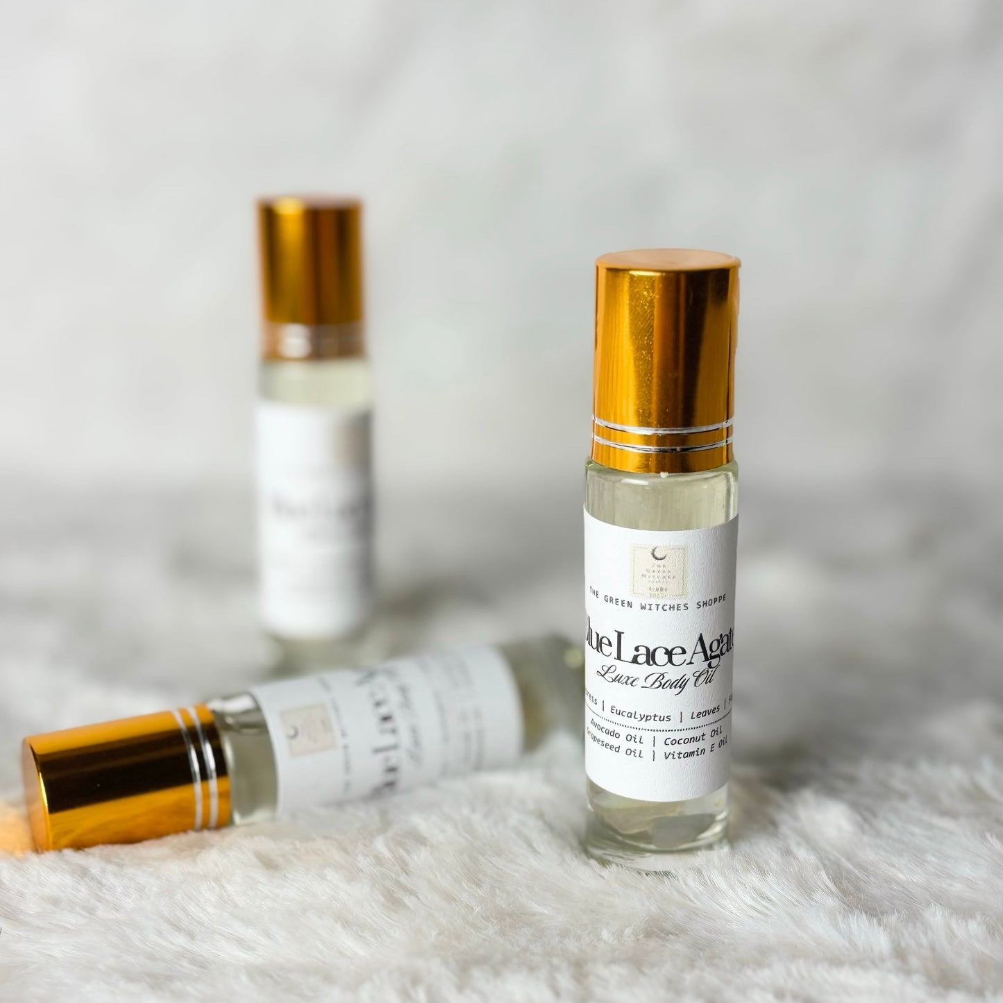 Three bottles of facial oil with gold caps on a white fur surface