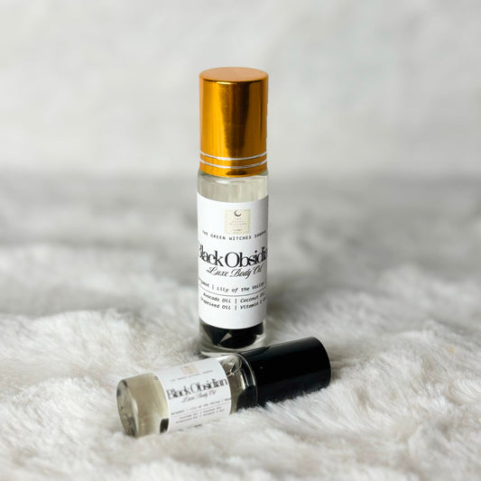 Two small roller bottles of 'Black Orchid' perfume on a white fur surface.