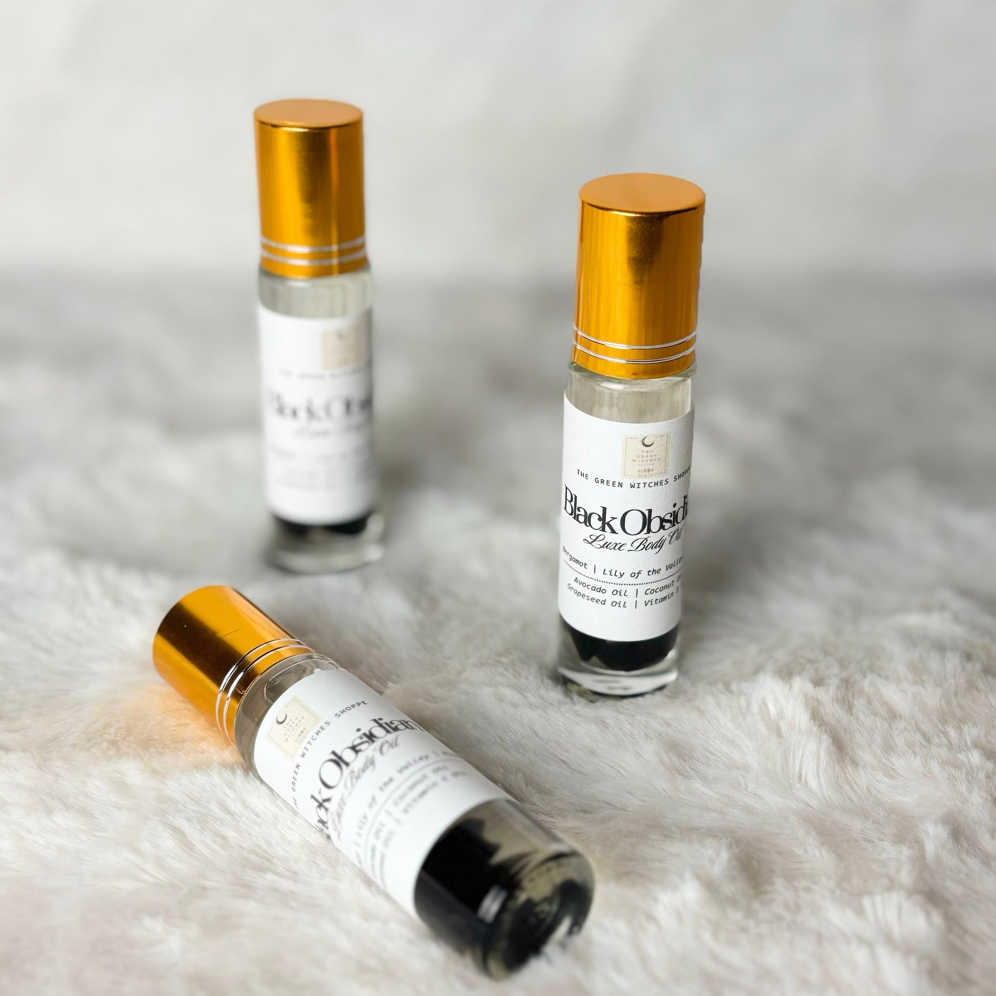 Three small glass bottles with gold caps on a textured white surface