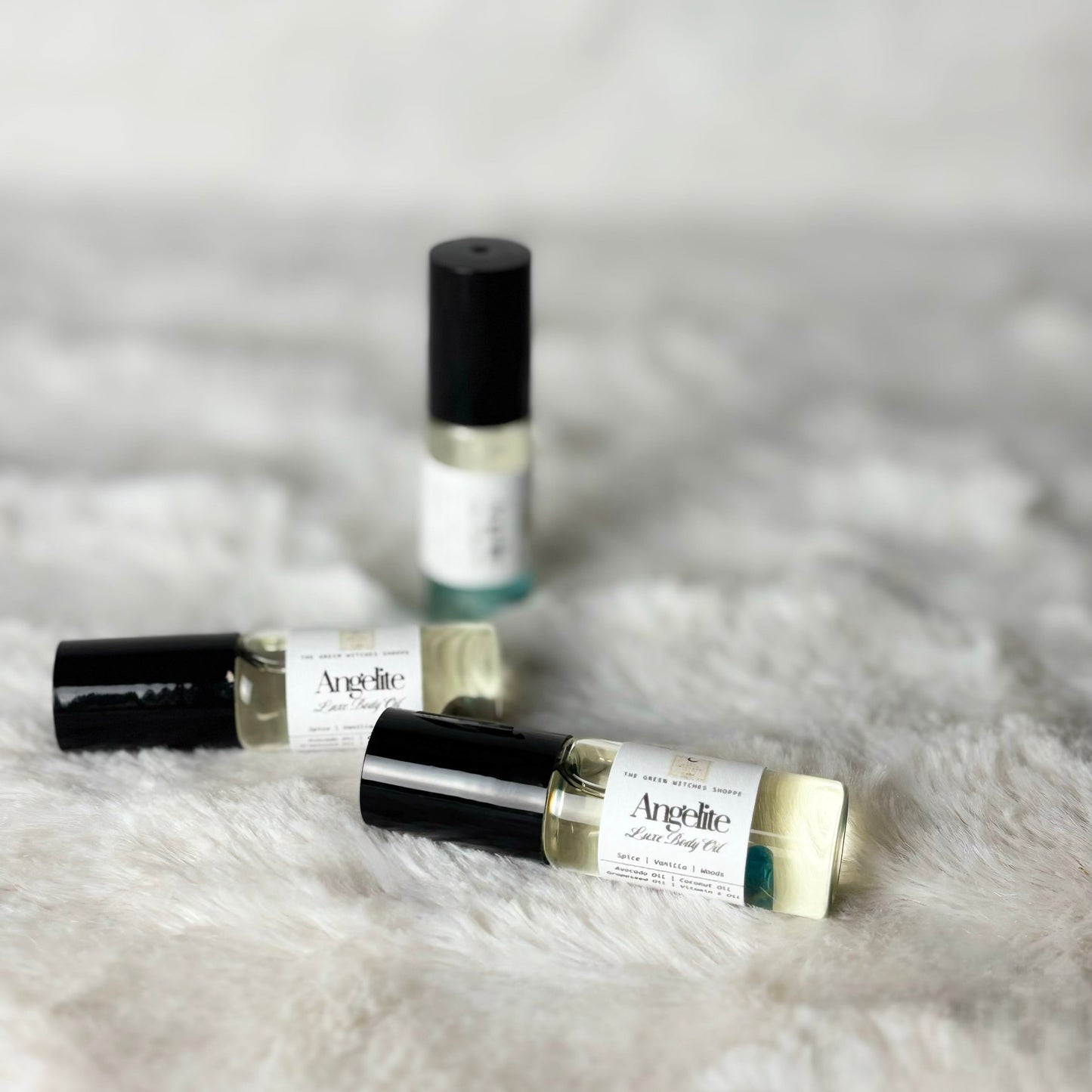 Three small perfume bottles with black caps on a fluffy white surface