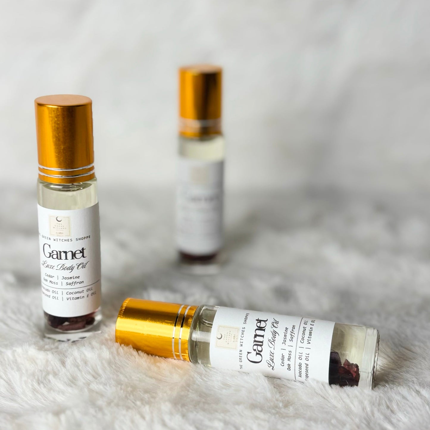 Three small bottles of Gamet Elixir Body Oil on a textured white surface