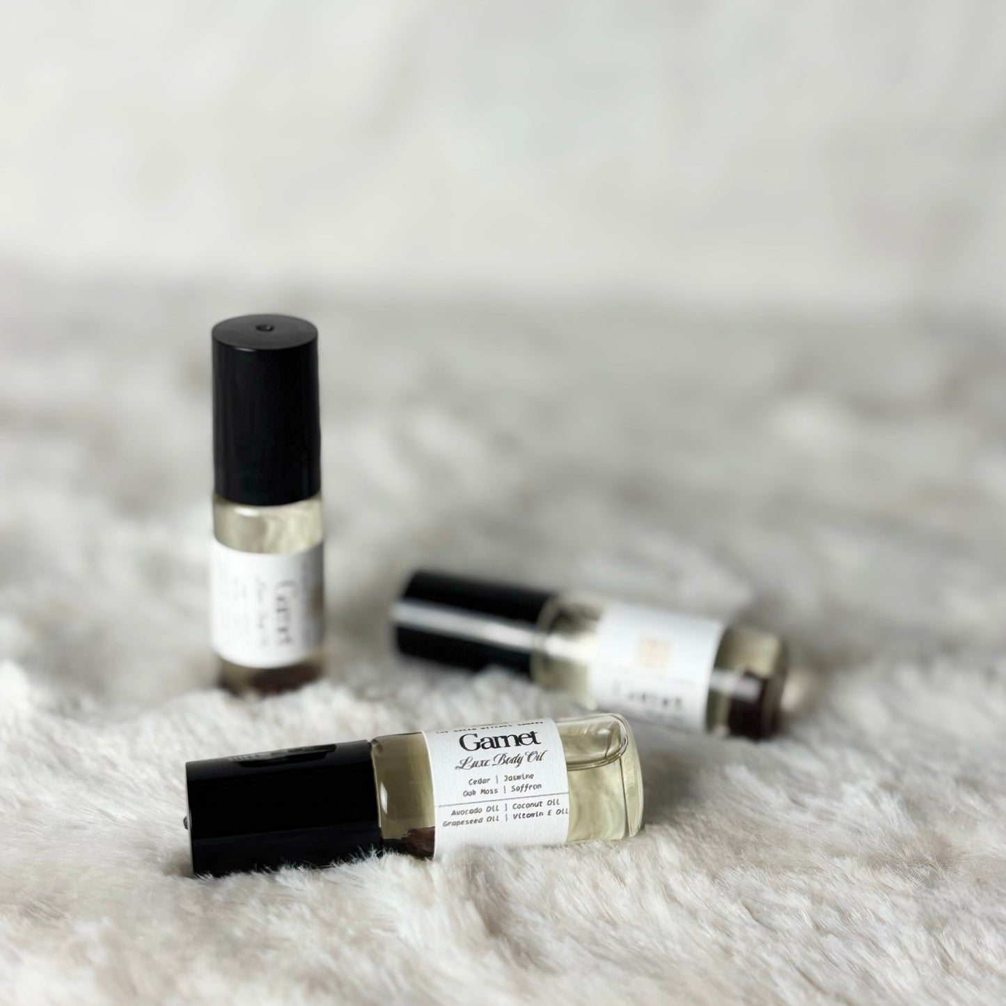 Three small perfume bottles on a textured white surface