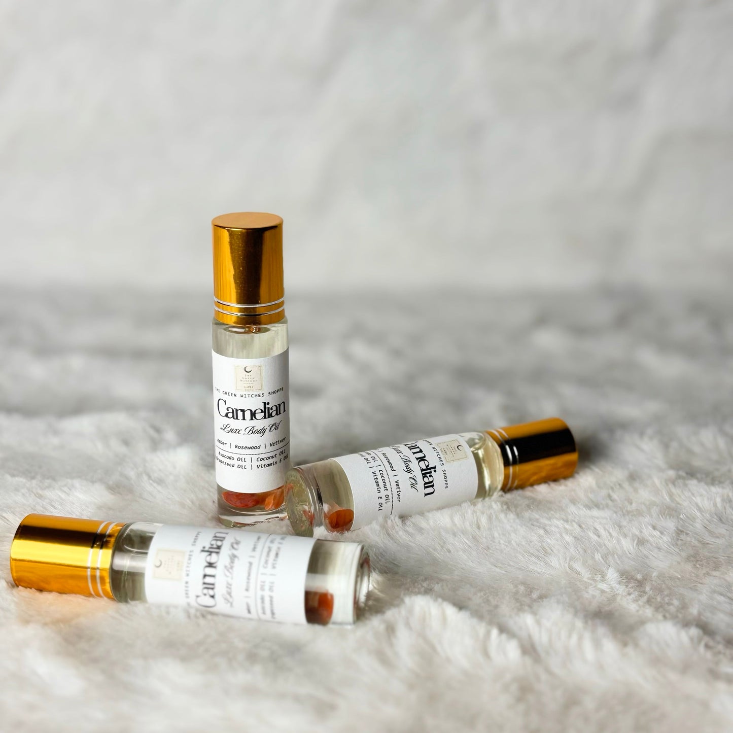 Three small perfume bottles with gold caps on a textured white surface