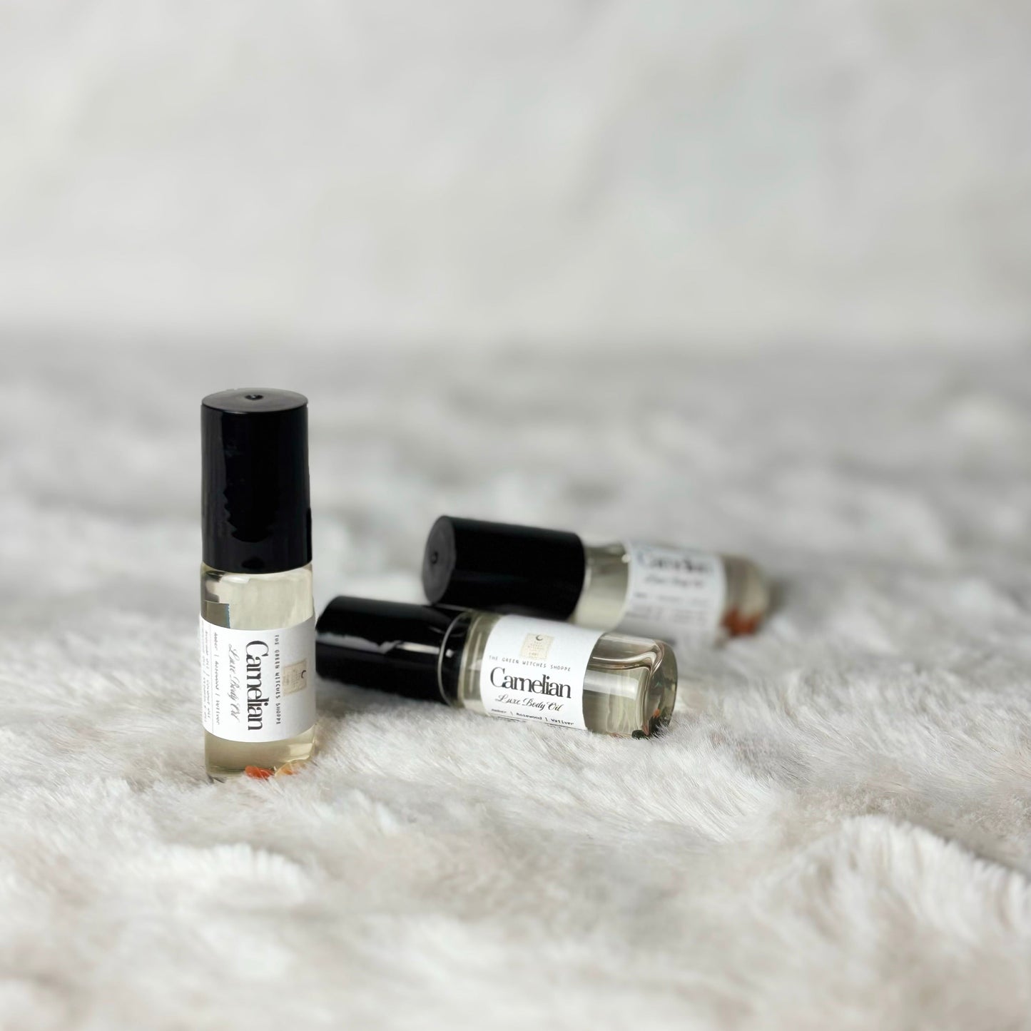 Four small rollerball bottles labeled 'Candle' on a textured white surface.