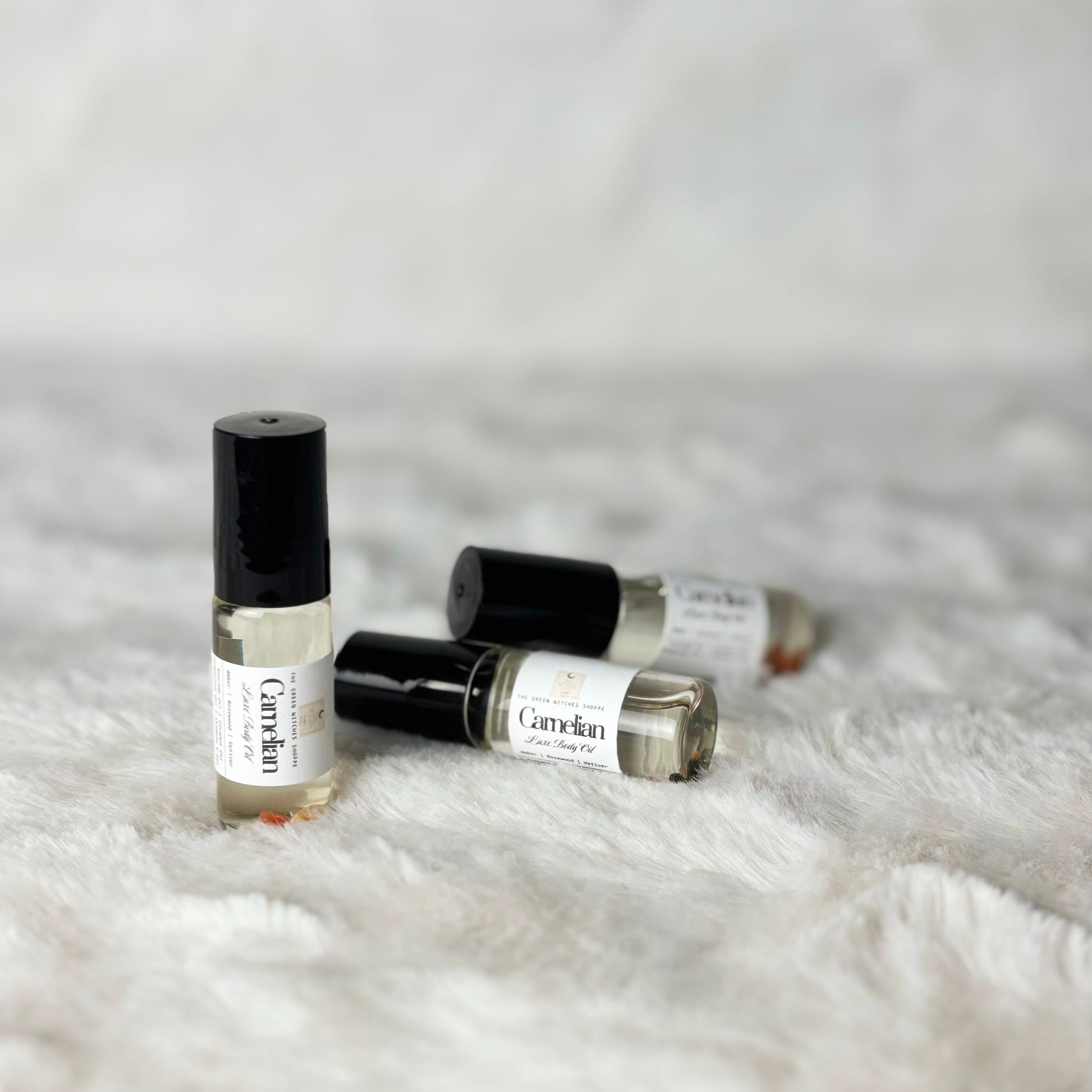 Four small rollerball bottles labeled 'Candle' on a textured white surface.