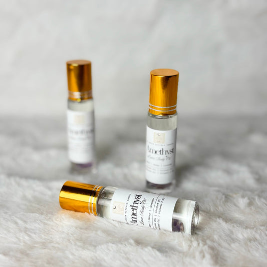 Three small perfume bottles with gold caps on a textured white surface