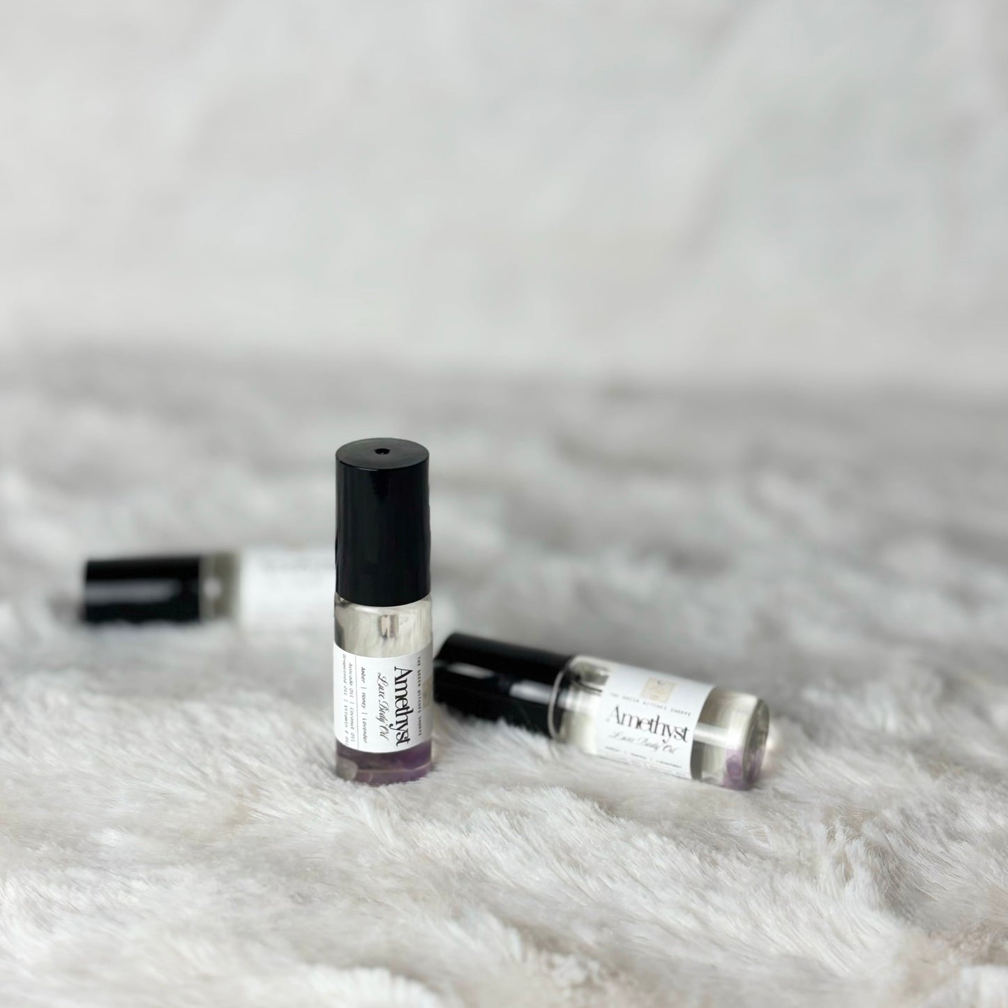 Two small perfume bottles with labels on a white fur surface