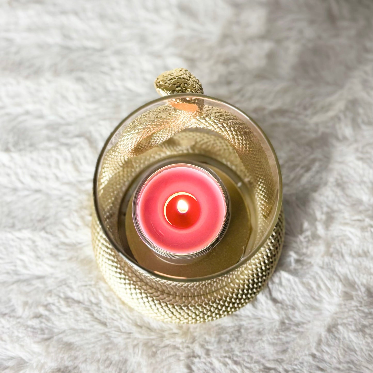 Gold decorative item with a pink center on a white fur surface