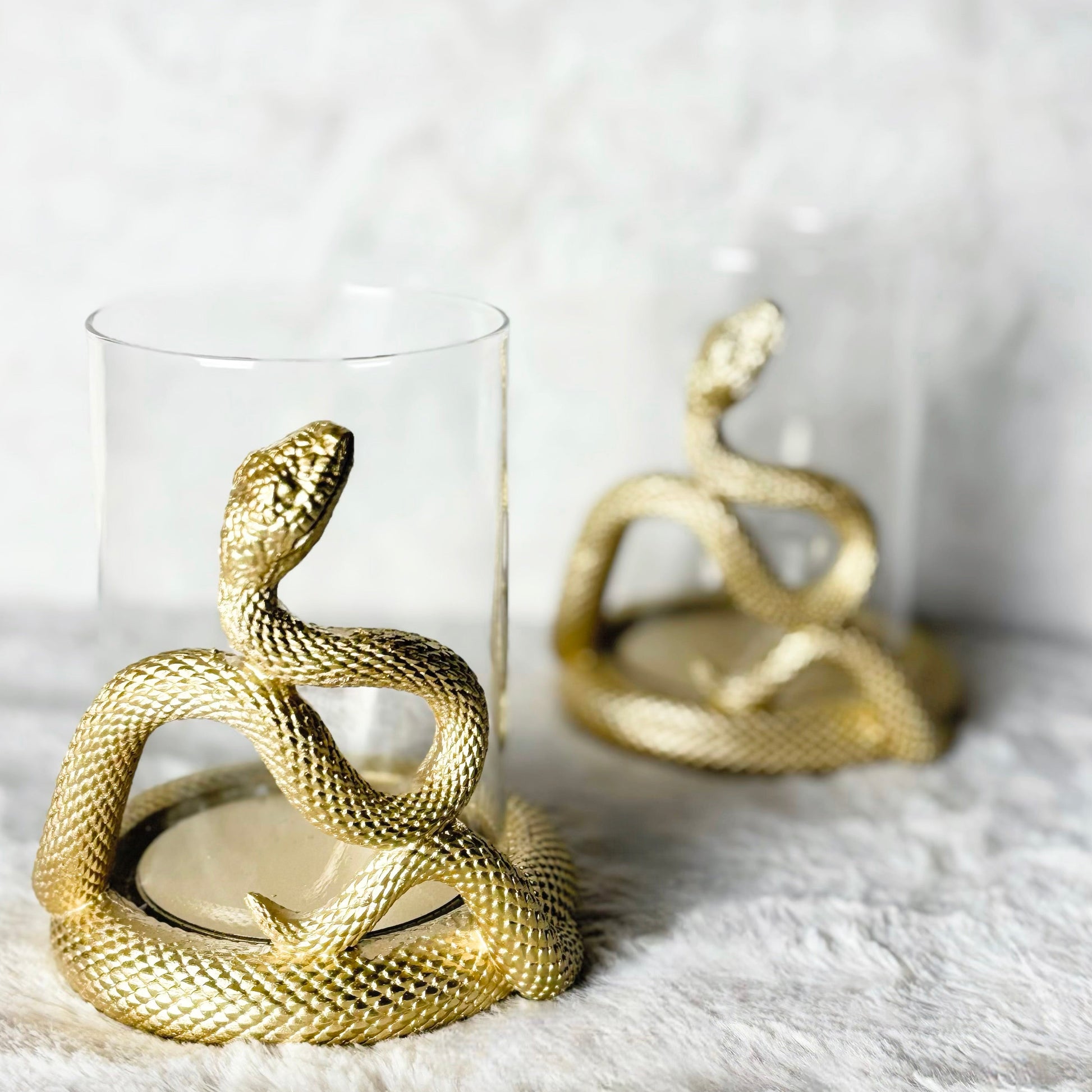 Gold snake decorative items on a white surface with a light gray background