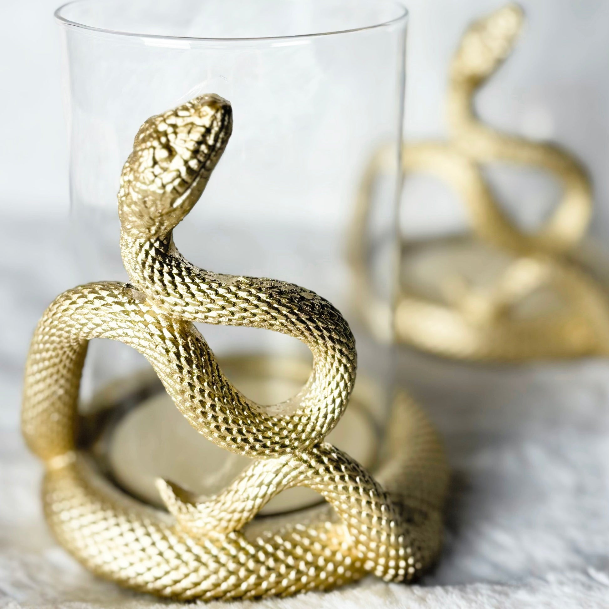Gold snake-shaped candle holders on a white surface