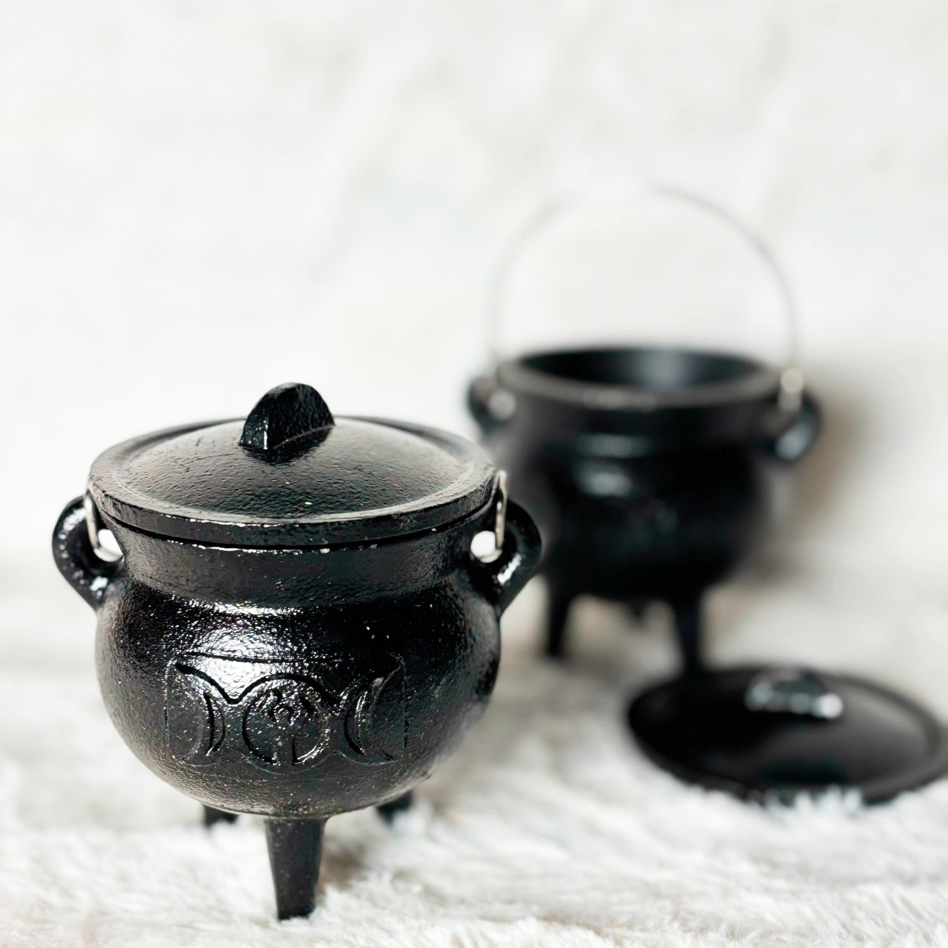 Black cauldron with lid on a white surface