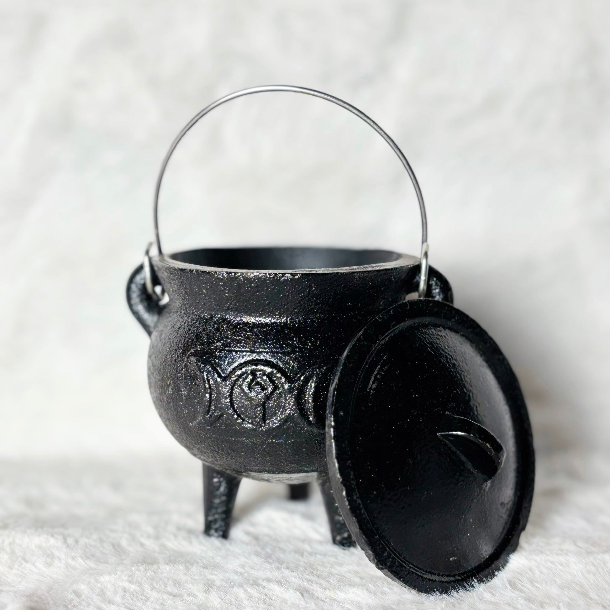 Black cauldron with lid on a white textured background