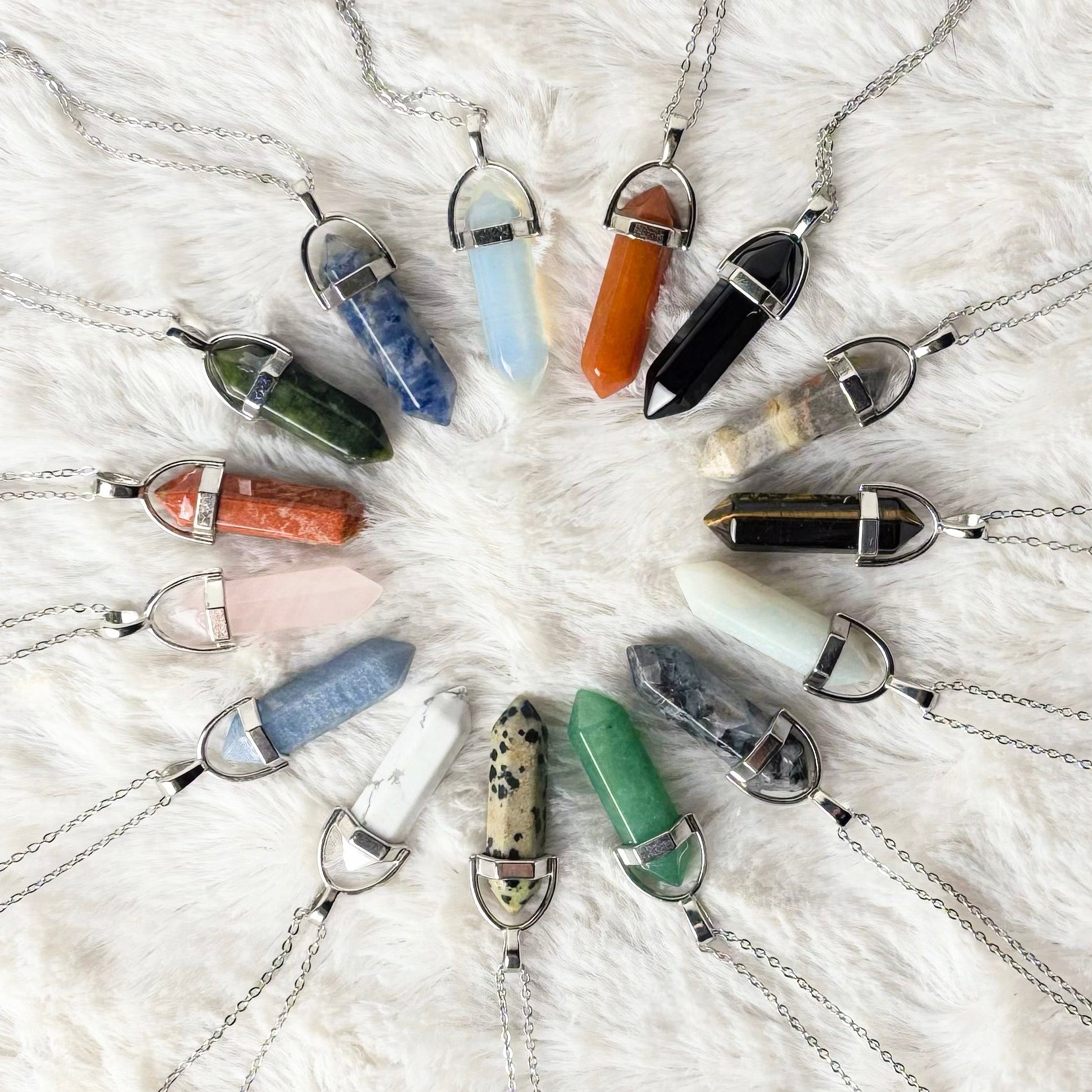 Necklaces with colorful pendant beads arranged in a circular pattern on a textured white surface.