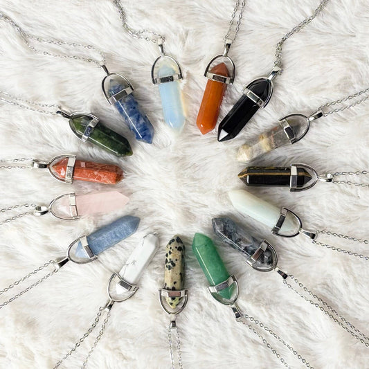 Necklaces with colorful pendant beads arranged in a circular pattern on a textured white surface.